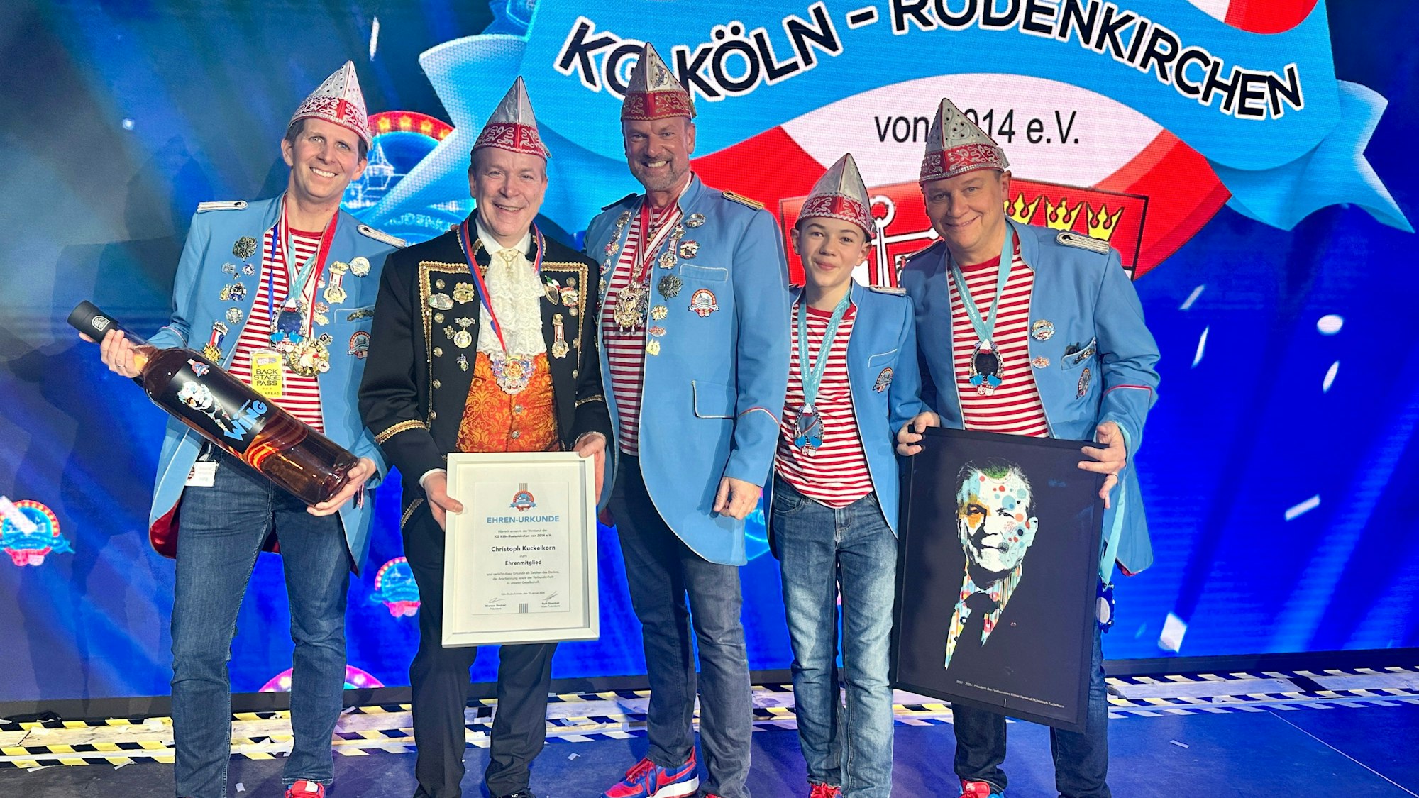 Mitglieder der KG Köln Rodenkirchen stehen in hellblauen Blazern und rot-weißen Ringelshirts rechts und links von Festkomitee-Präsident Christoph Kuckelkorn.
