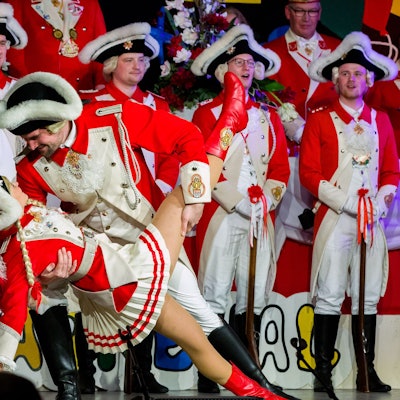 Auf einer Bühne stehen Mitglieder einer Karnevalsgesellschaft, im Vordergrund ein Tanzpaar in Aktion.