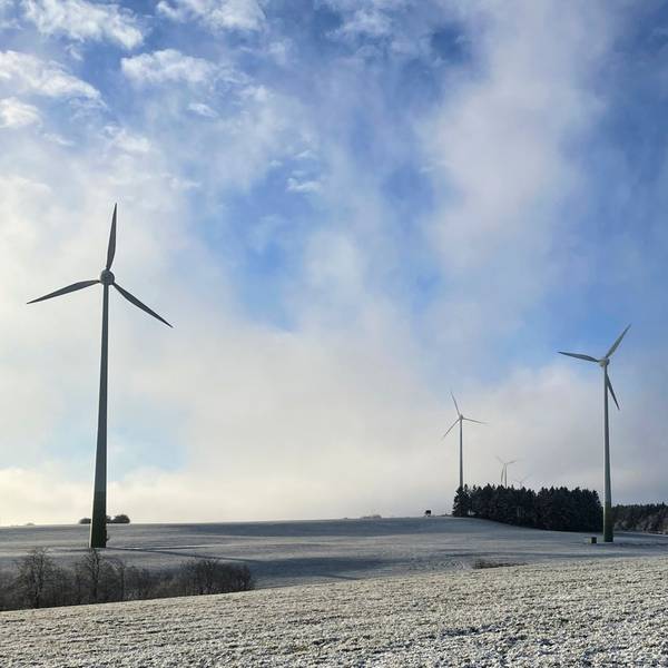 Windräder im Hellenthaler Höhengebiet bei Oberreifferscheid stehen auf einer verschneiten Wiese.