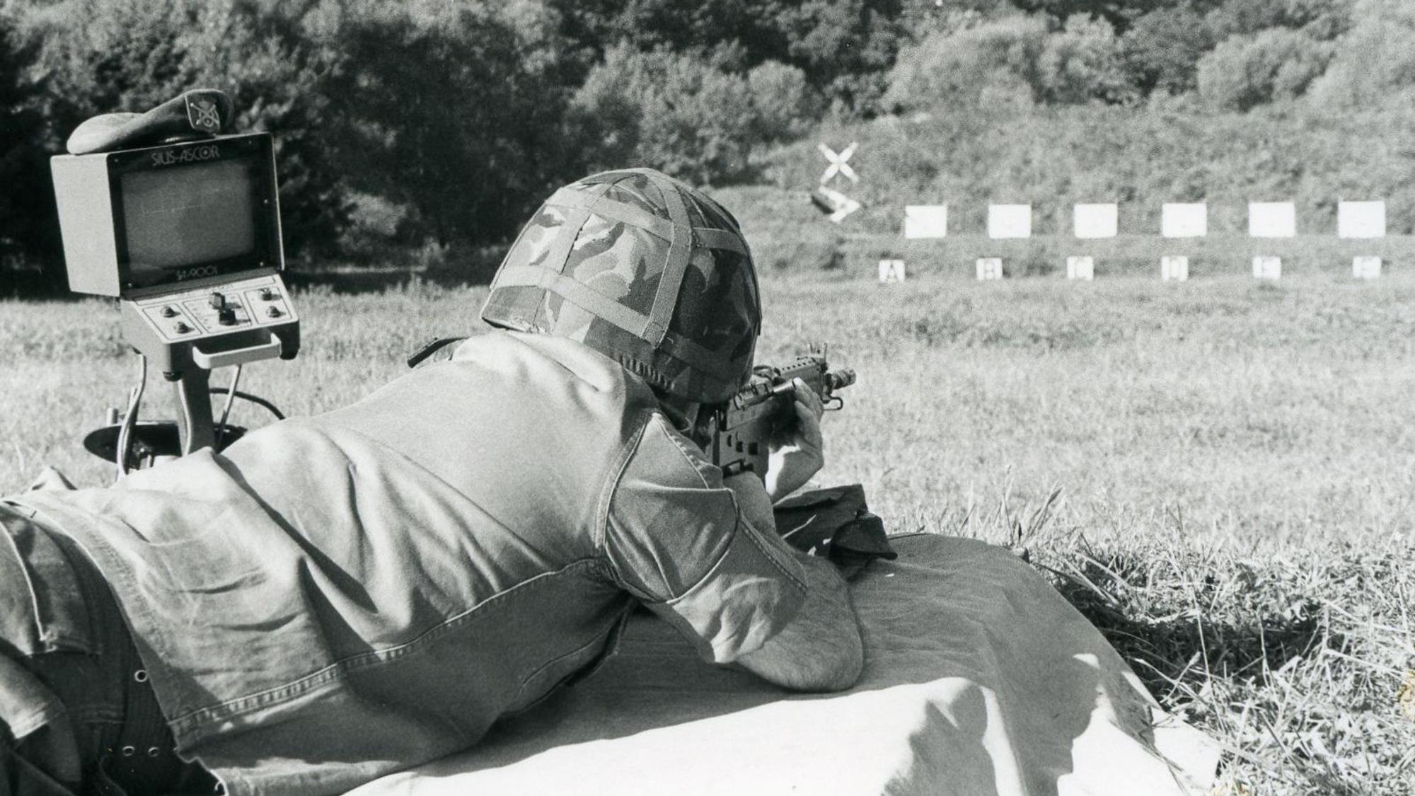 Ein Soldat mit Stahlhelm visiert im Liegen Zielscheiben an.
