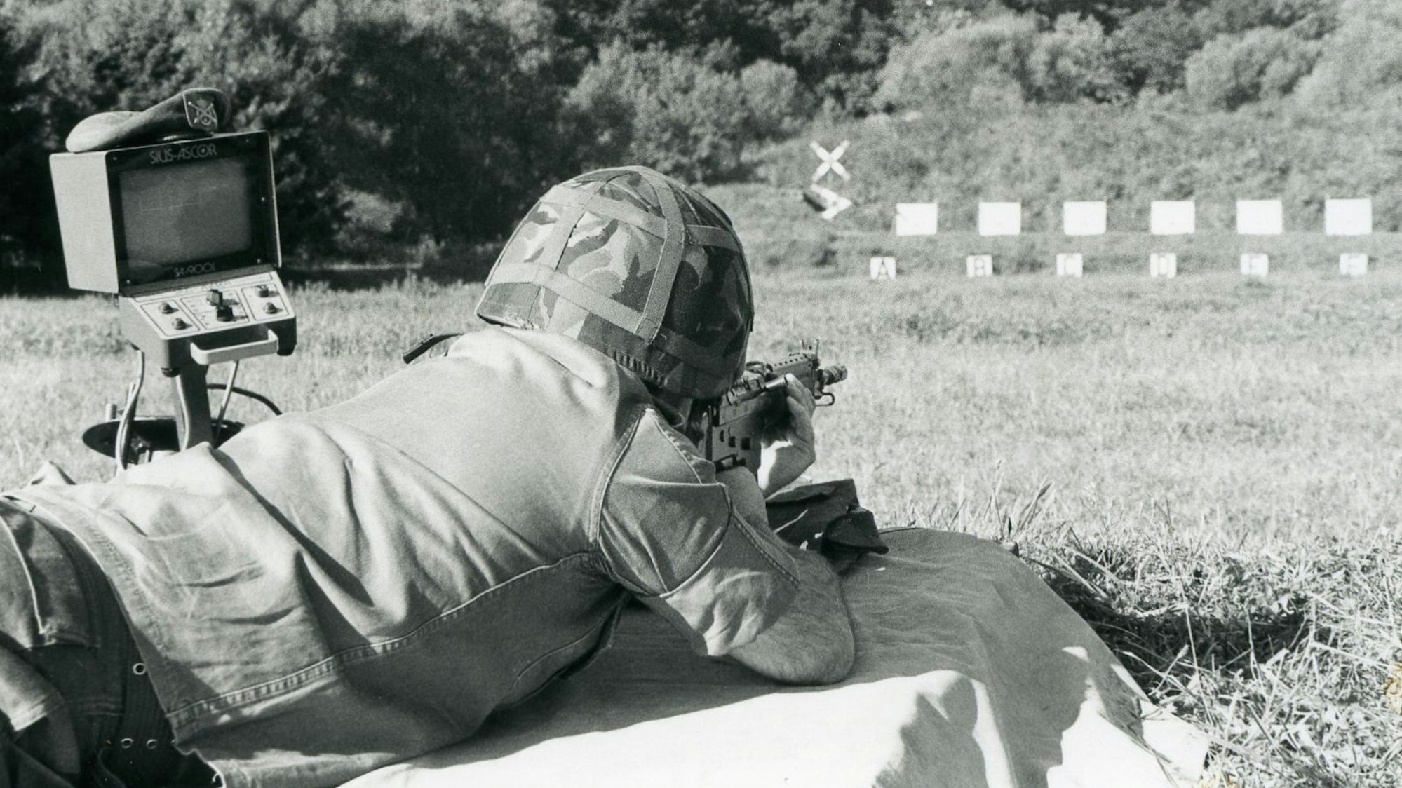 Ein Soldat mit Stahlhelm visiert im Liegen Zielscheiben an.