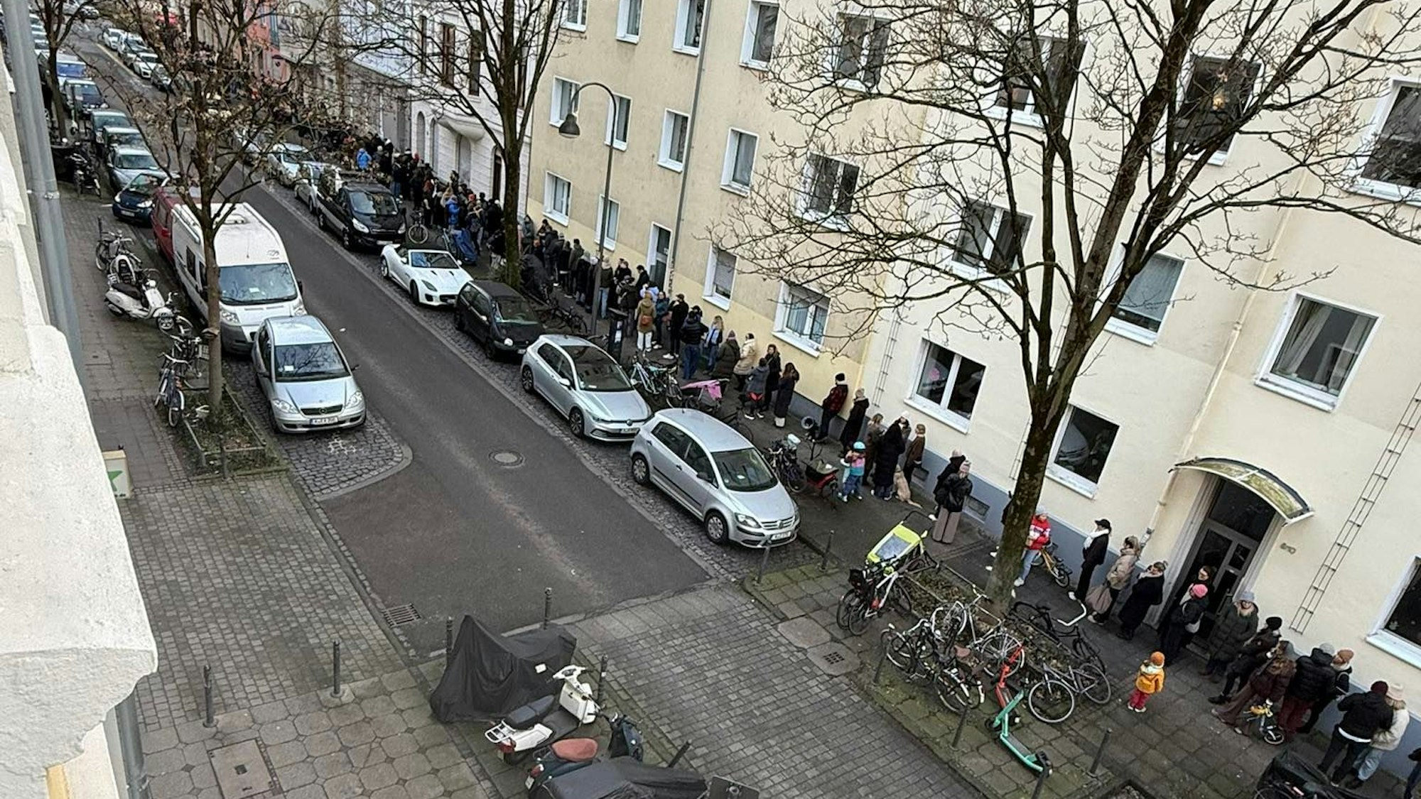 Menschen stehen auf einem Bürgersteig in einer langen Schlange.