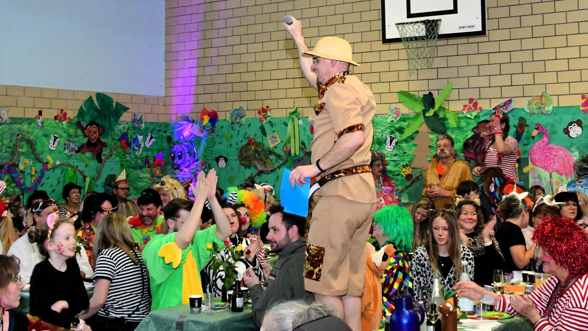 Zwischen den kostümierten Jecken steht ein Mann im Safari-Look auf dem Tisch.