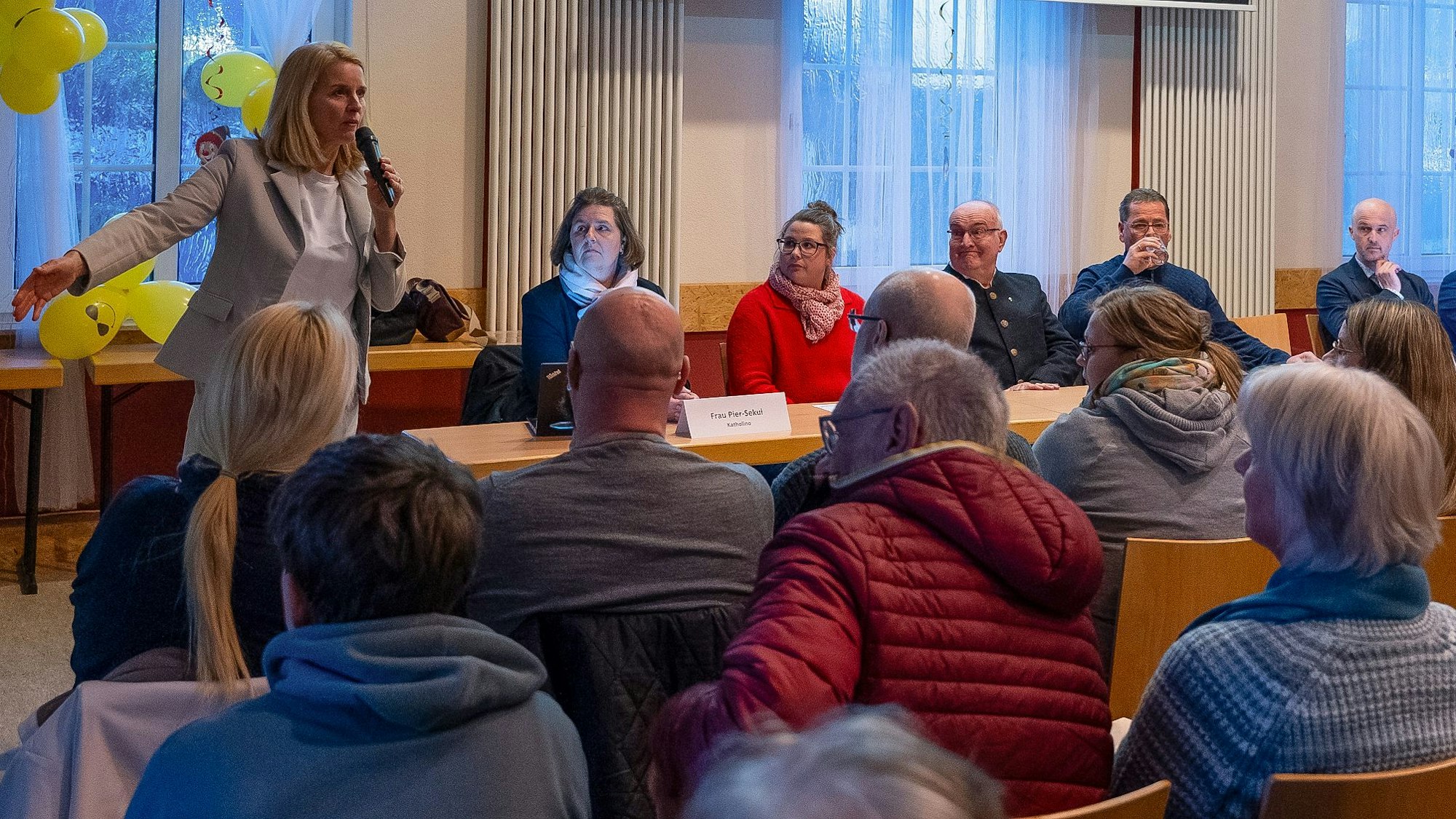 Eine Bürgermeisterin spricht auf einer Bürgerversammlung.