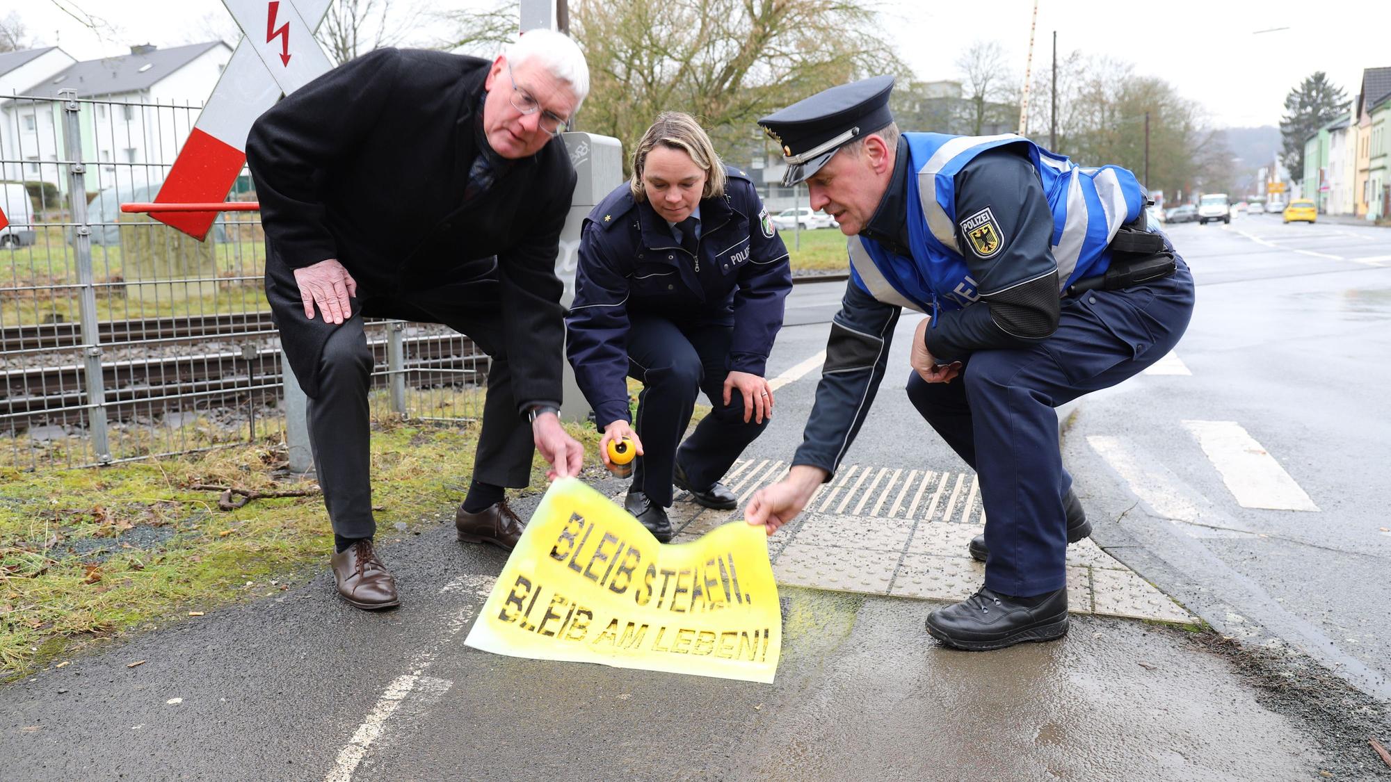 Landrat Sebastian Schuster, die Leiterin der Direktion Verkehr, Stephanie Spengler, und der Präventionsbeautragte der Bundespolizei, Alexander Mauel, enthüllte den ersten aufgesprühten Schriftzug.