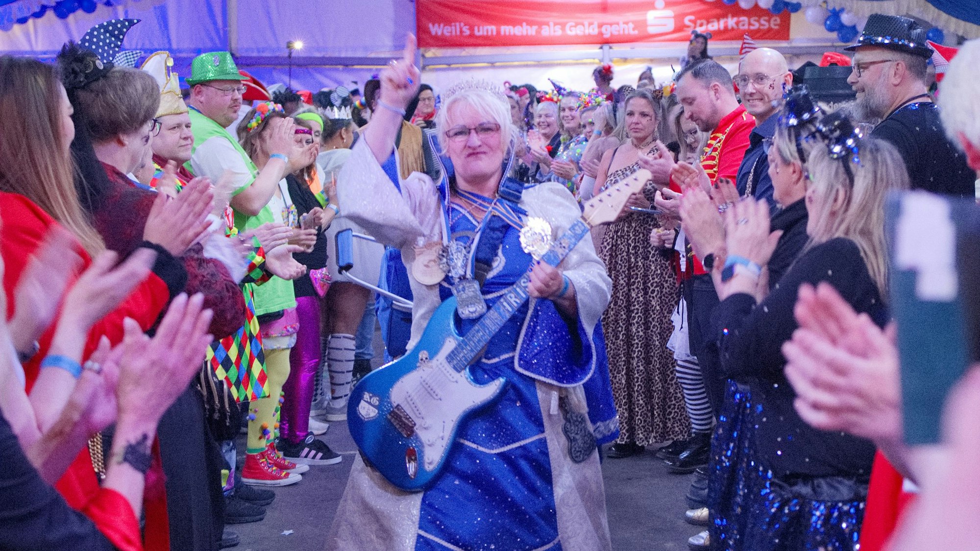 Das Bild zeigt die Tollität Iris I. (Erdmenger) auf dem Weg auf die Bühne. Sie trägt eine E-Gitarre um den Hals.