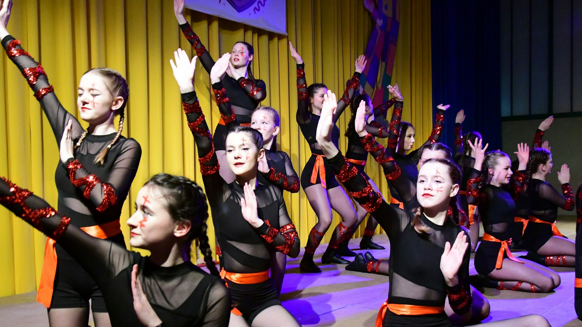 Junge Mädchen in schwarz-rotem Outfit tanzen.