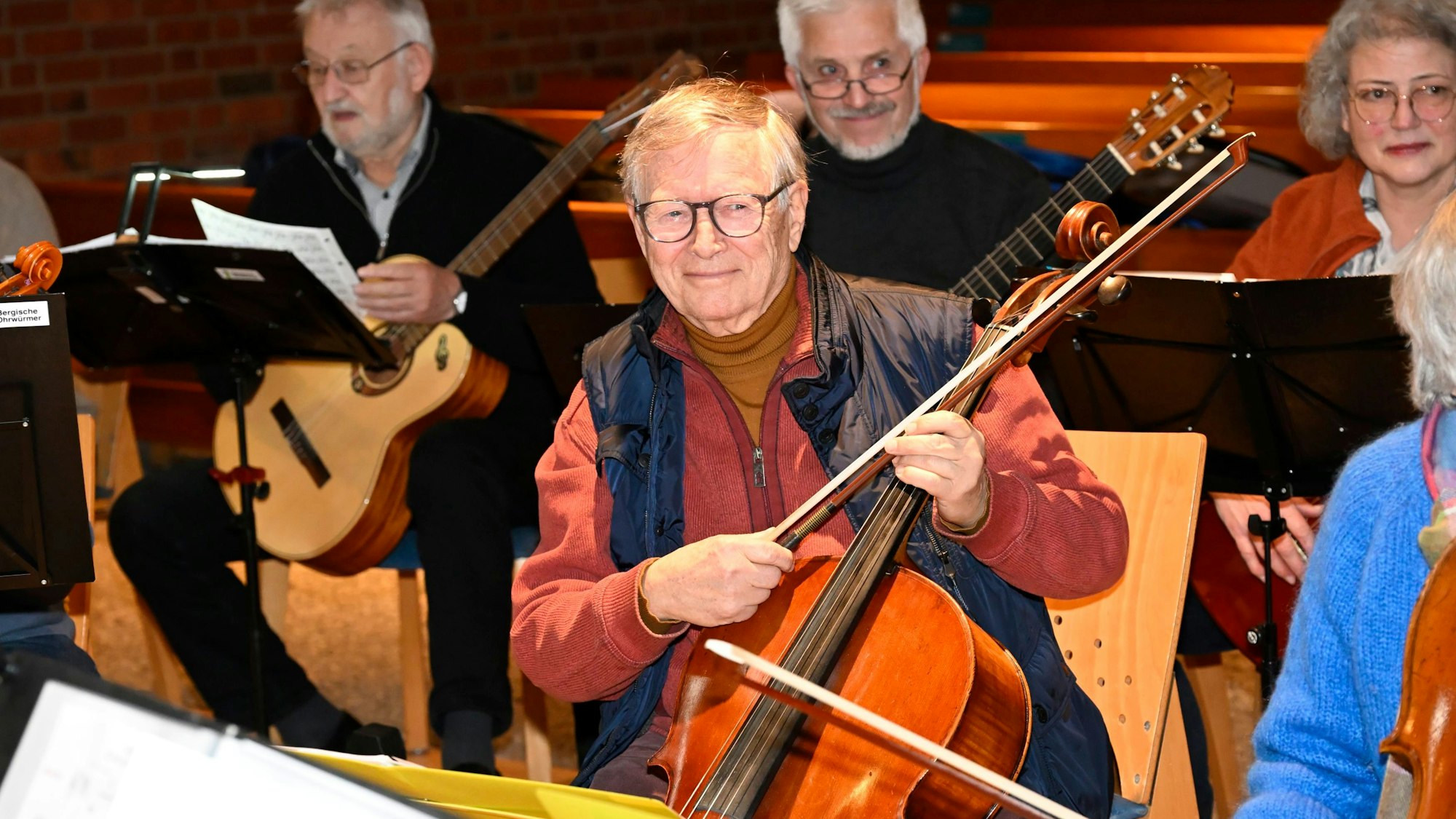 Der Cellist sitzt mit seinem Instrument auf einem Stuhl.