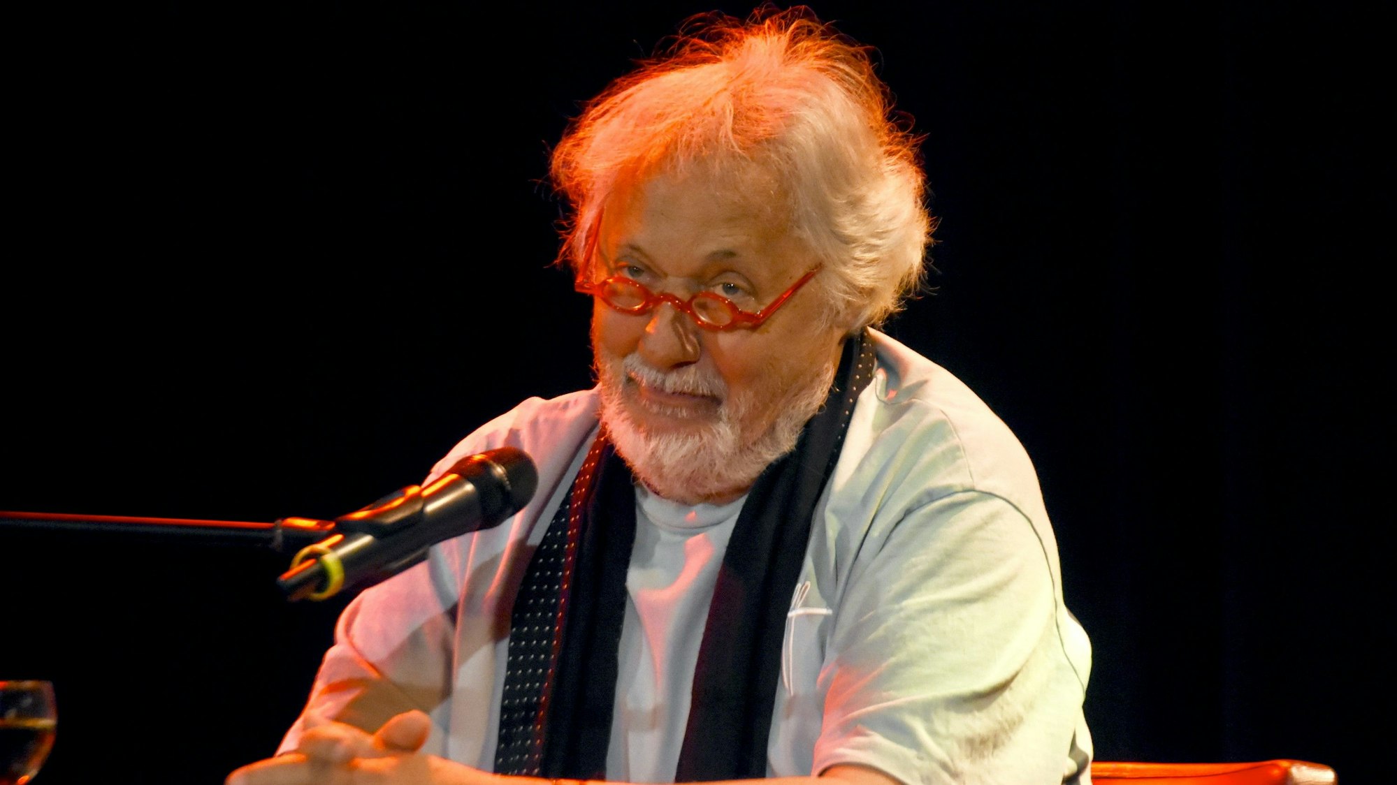 Konrad Beikircher sitzt vor einem Mikro.