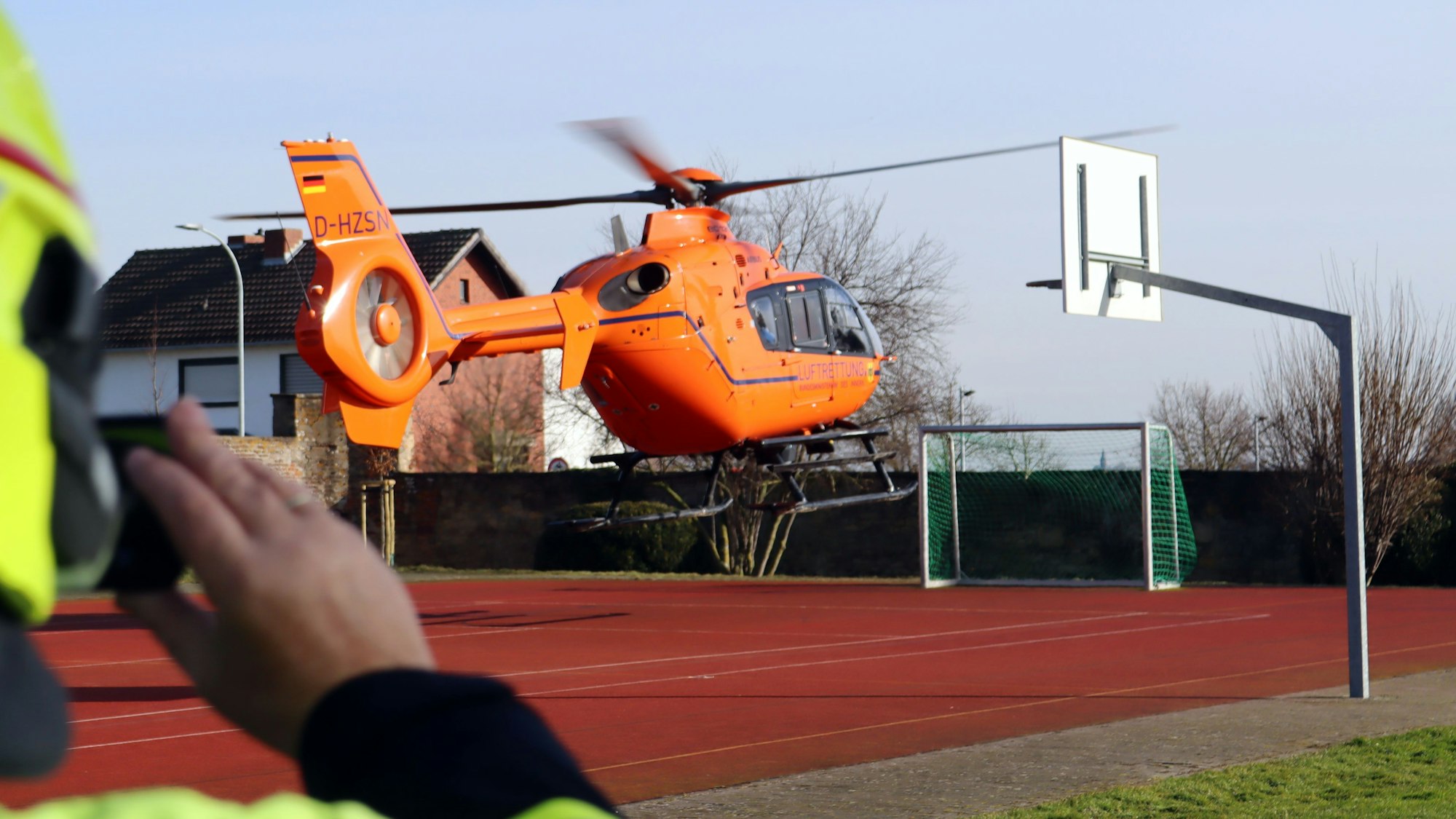Ein Hubschrauber startet von einer Tartan-Sportanlage aus.