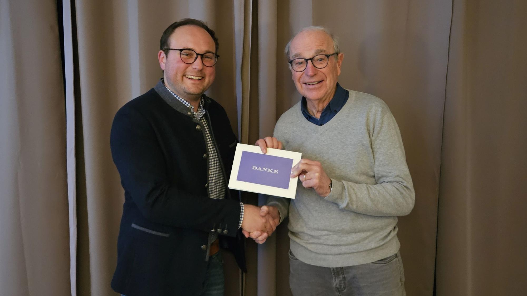 Das Foto zeigt zwei Männer, die ein Stück Papier mit der Aufschrift „Danke“ in der Hand halten.