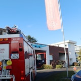 Ein Feuerwehrauto steht in der Einfahrt zu einer Fachklinik. Im Hintergrund sind Feuerwehrleute zu erkennen.
