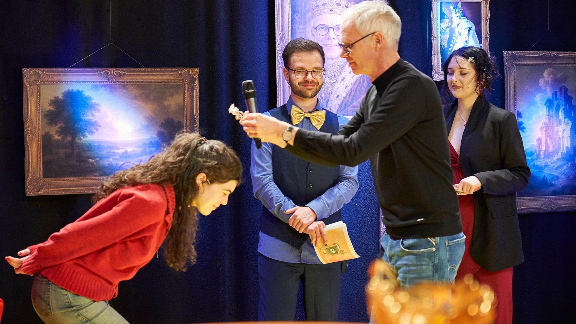 Ein Mann setzt bei einer Spieleshow einer Studentin eine Krone auf den Kopf.