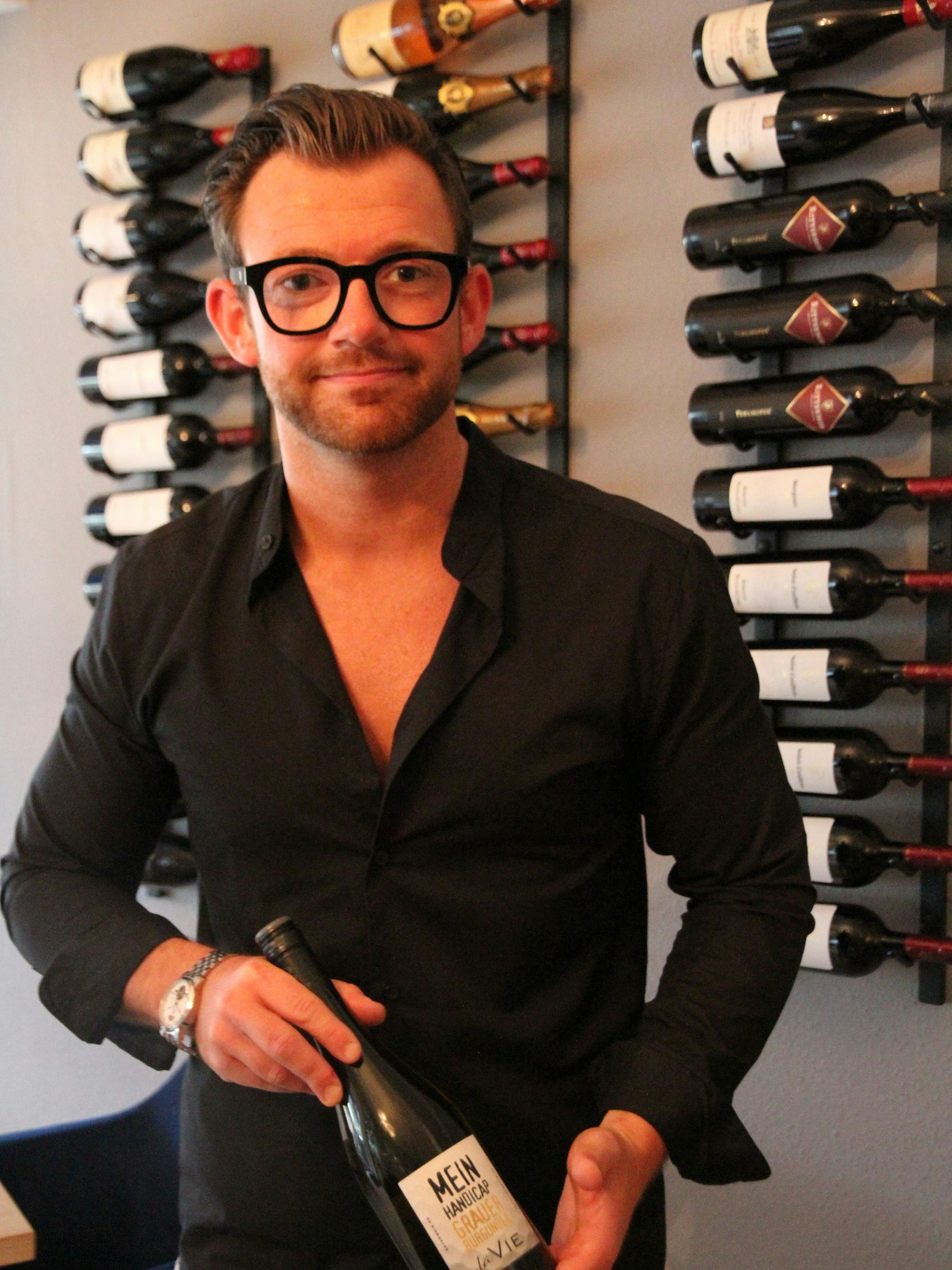 Ein Mann vor einem Weinregal