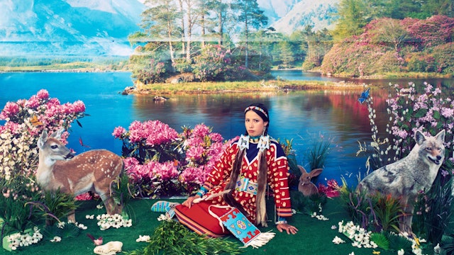 Wendy Red Star sitzt in einer kitschigen Naturkulisse.