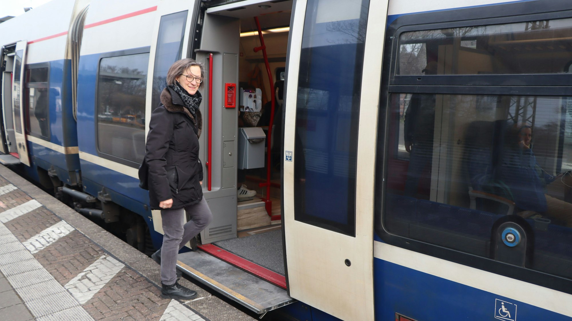 Das Foto zeigt eine Frau, die in eine Regionalbahn einsteigt.