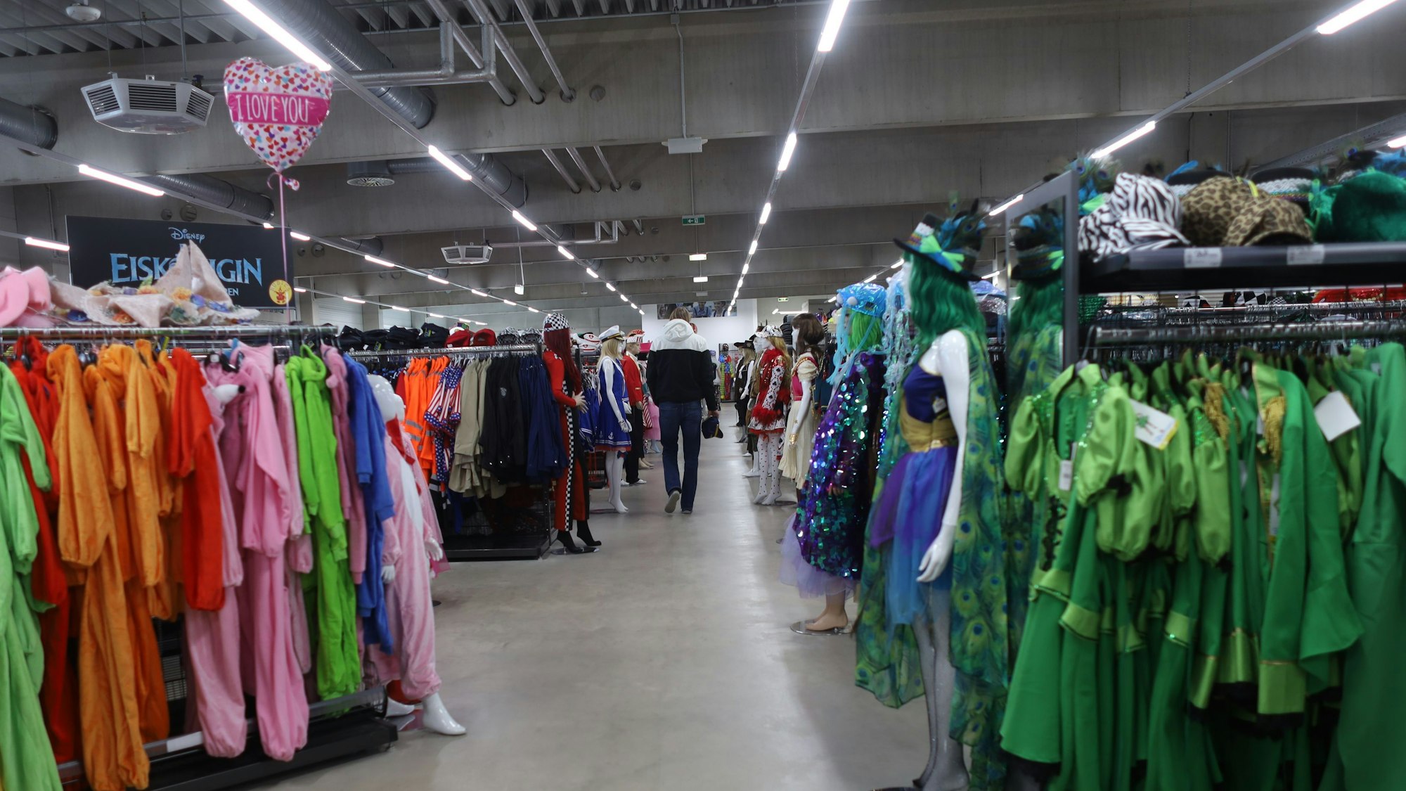 Aufnahme von langen Reihen mit Regalständern, auf denen Kostüme nach Farben sortiert hängen.