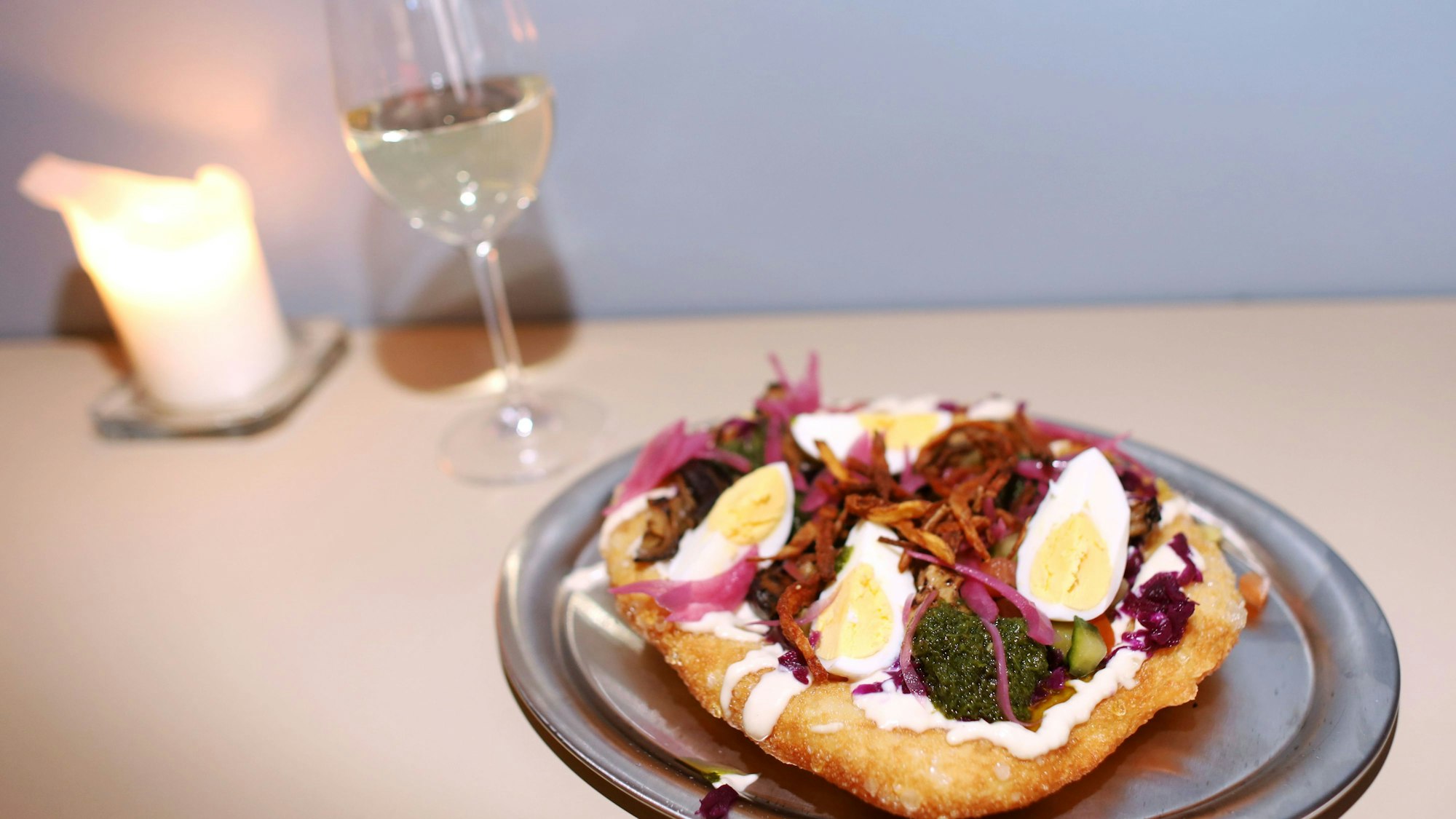 Langos mit Wein, daneben eine Kerze