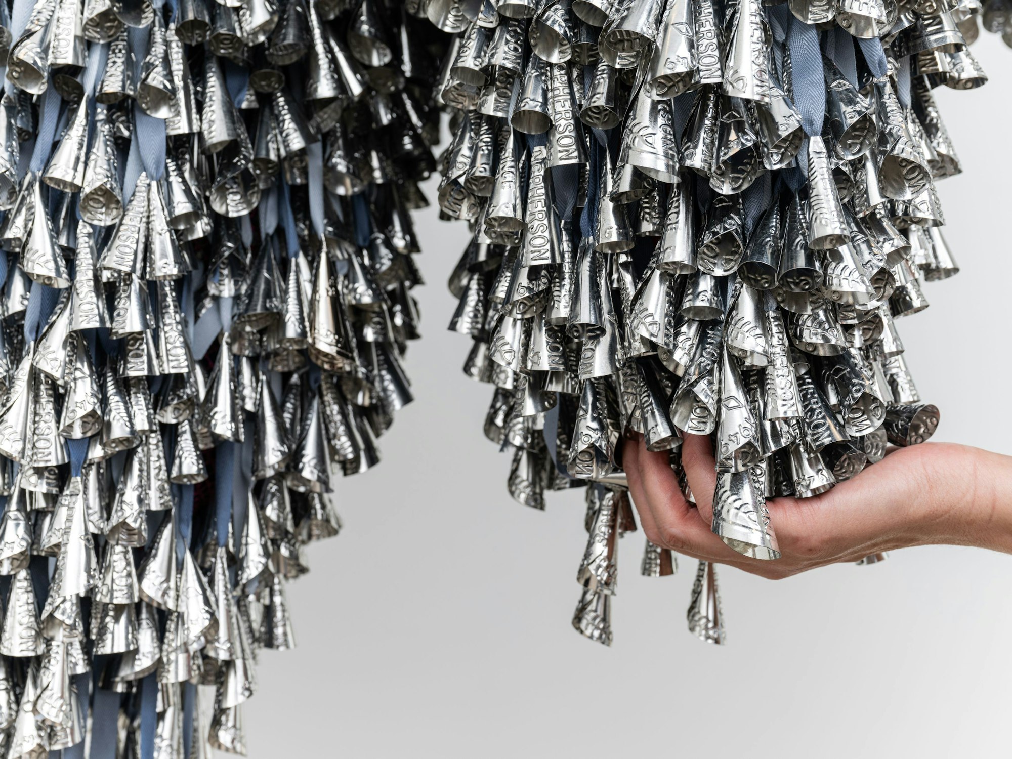 Eine Hand betastet eine „Wolke“ aus Schellen.