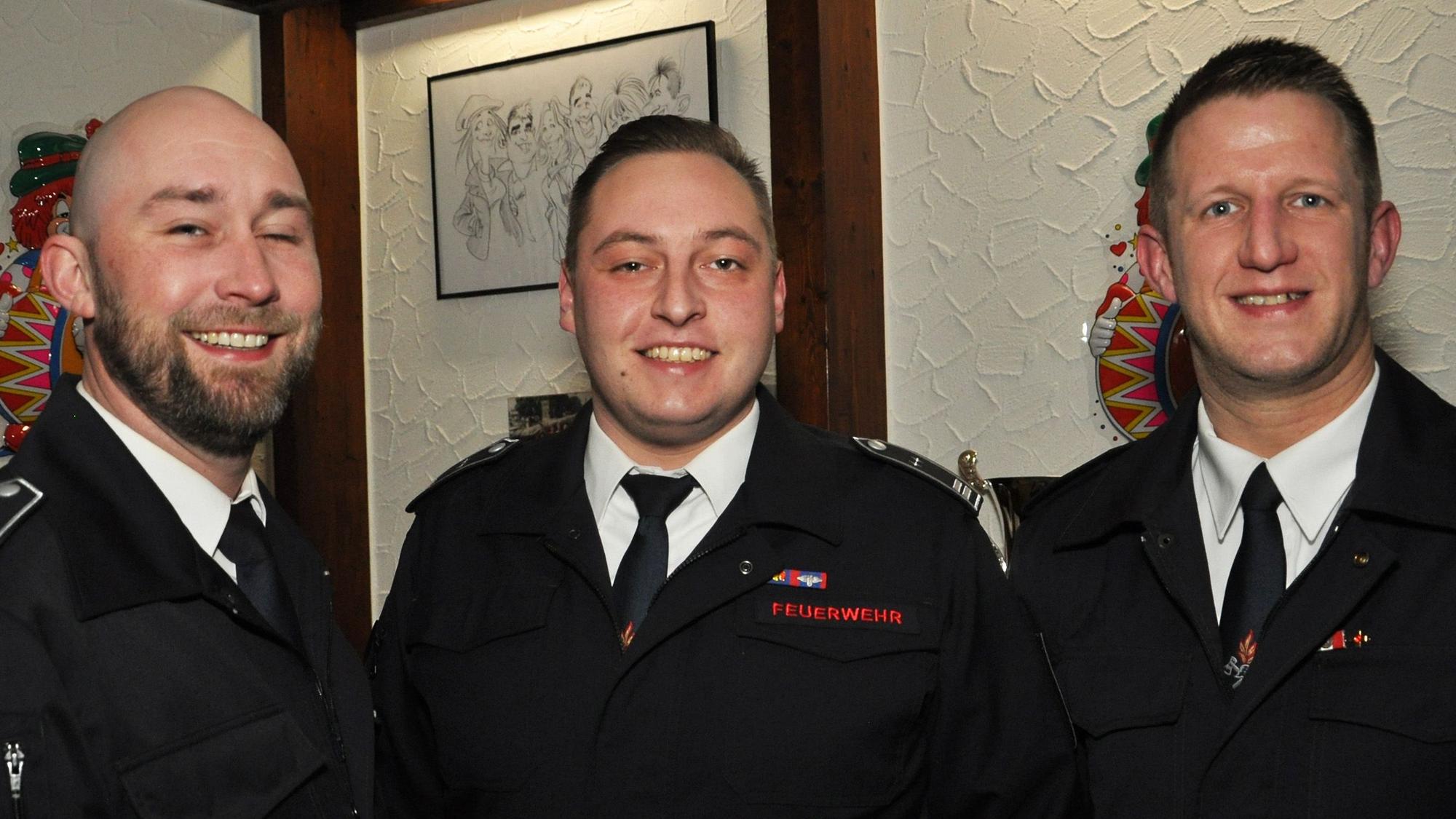 Drei Männer in Uniformen stehen nebeneinander und schauen in die Kamera.