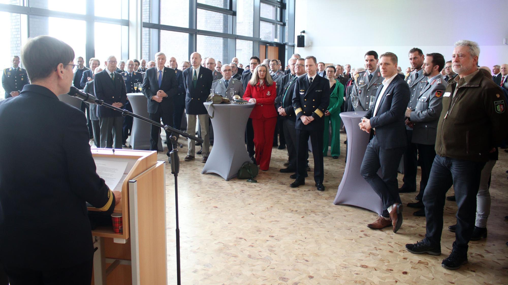 Flottillenadmiral Sabine Reppin ist von hinten am Rednerpult zu sehen. Sie blickt auf die 130 Gäste des Neujahresempfangs.