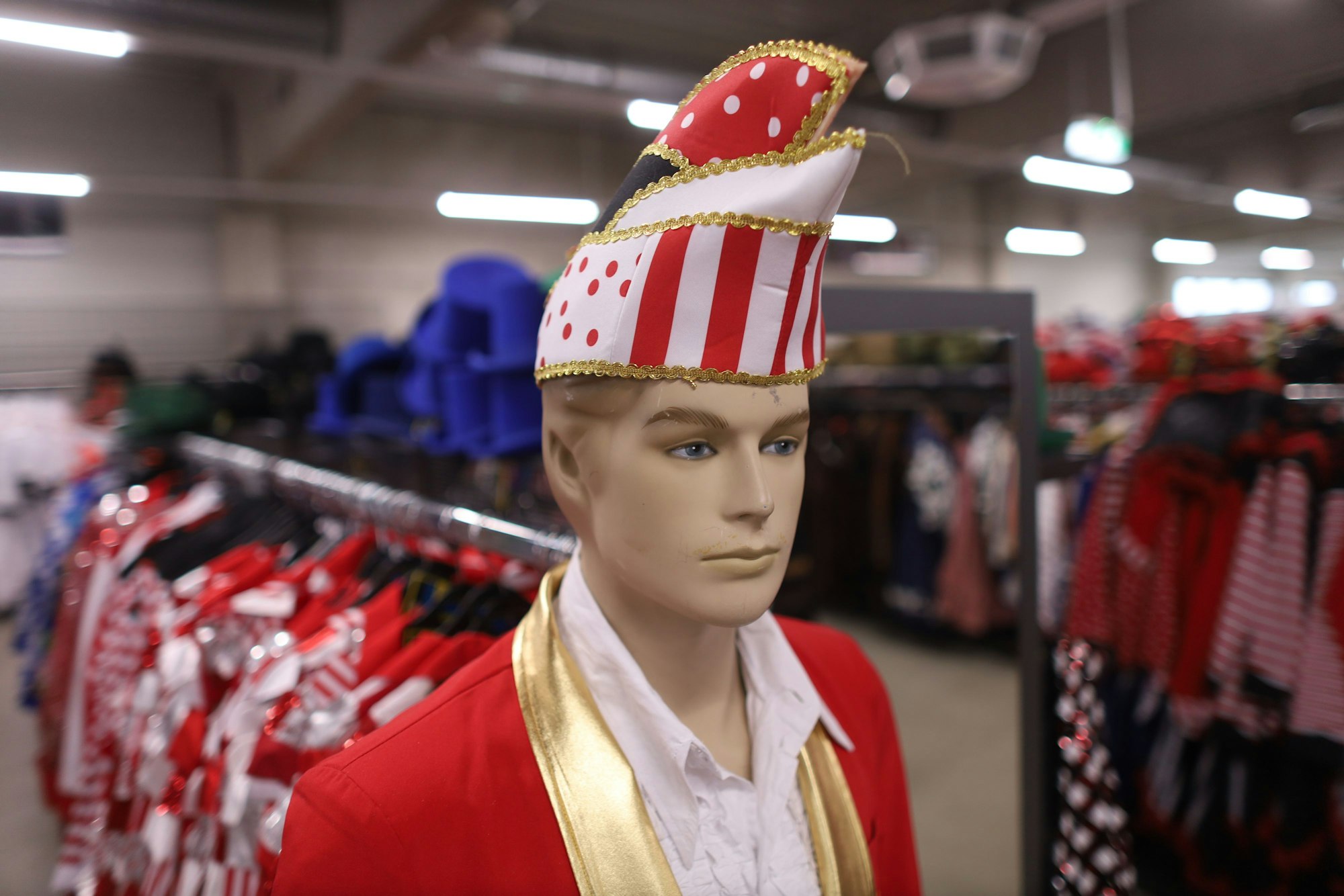 Schaufensterpuppe mit Karnevalsmütze, Jacke und Hemd in den Stadtfarben rot und weiß.