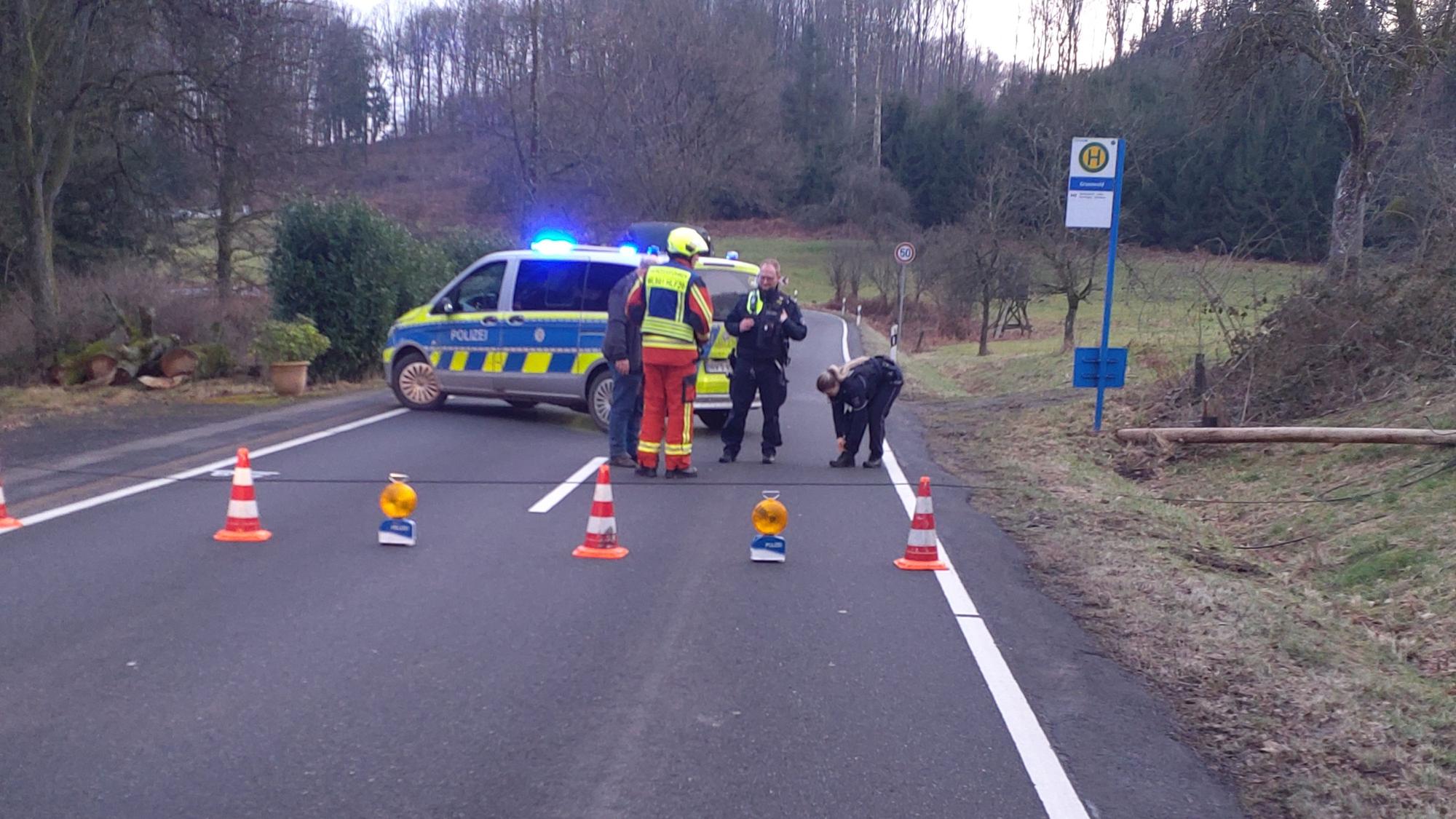 Polizei und Feuerwehr sichern in der Waldbröler Ortschaft die Stelle, an der ein hölzener Kabelmast der Deutschen Telekom umgekippt ist. Der Mast landete im Grünen und nicht auf dem Asphalt der stark befahrenen Bundesstraße 256.