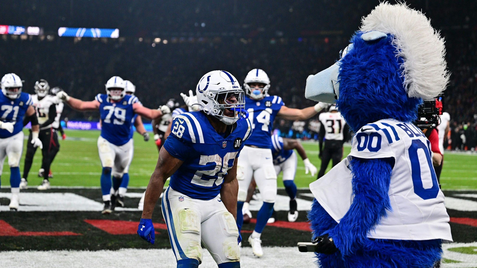 American Football: Profiliga NFL, Indianapolis Colts - Atlanta Falcons, Hauptrunde, Hauptrunde-Partien, 10. Spieltag, Olympiastadion Berlin. Jonathan Taylor (Indianapolis Colts) jubelt nach seinem dritten Touchdown mit Blue, dem offiziellen Maskottchen der Indianapolis Colts, über den Sieg in der Verlängerung. +++ dpa-Bildfunk +++