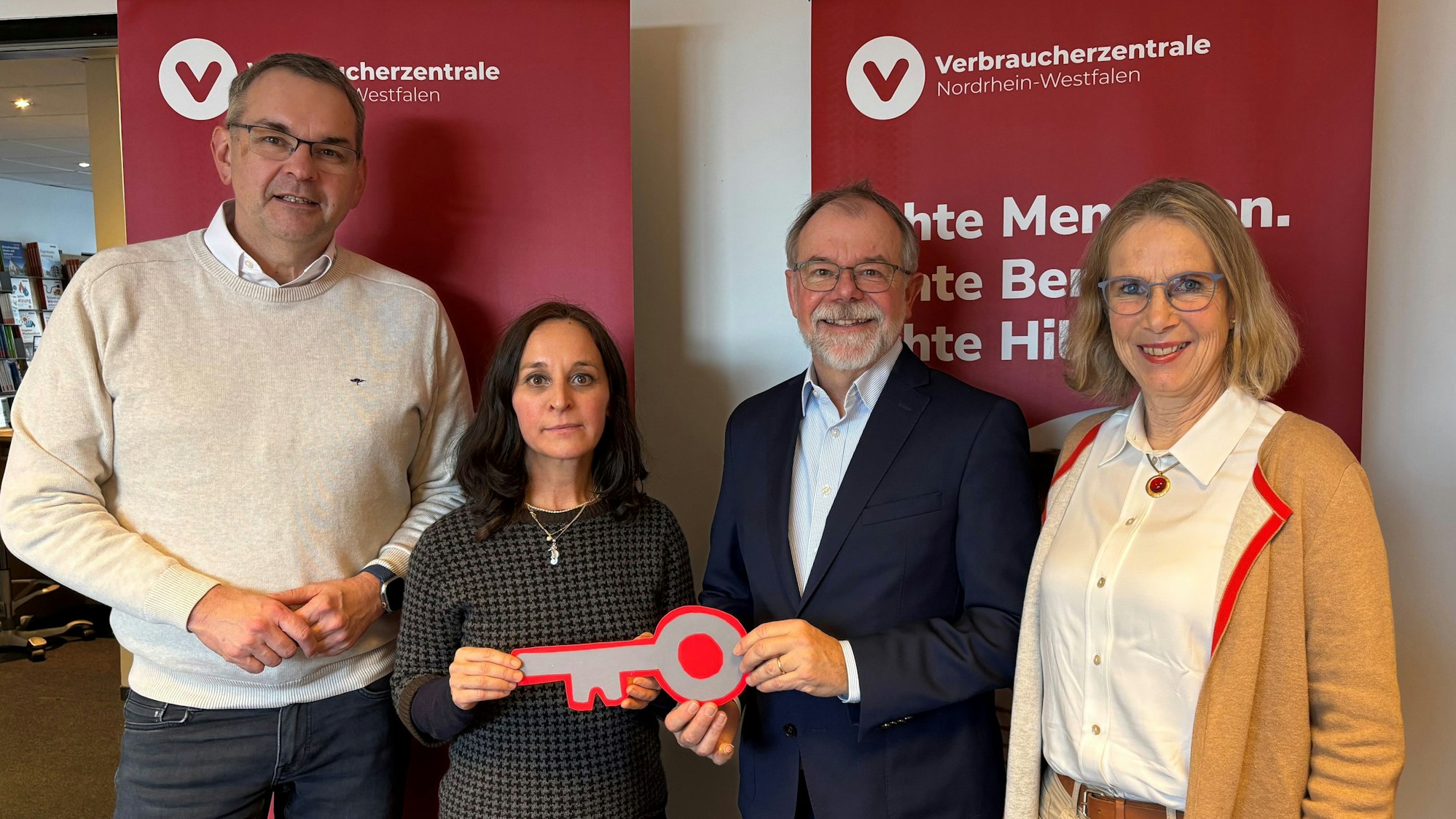 Ein Mann und eine Frau halten gemeinsam einen großen Pappschlüssel in den Händen. Alle lachen in die Kamera.