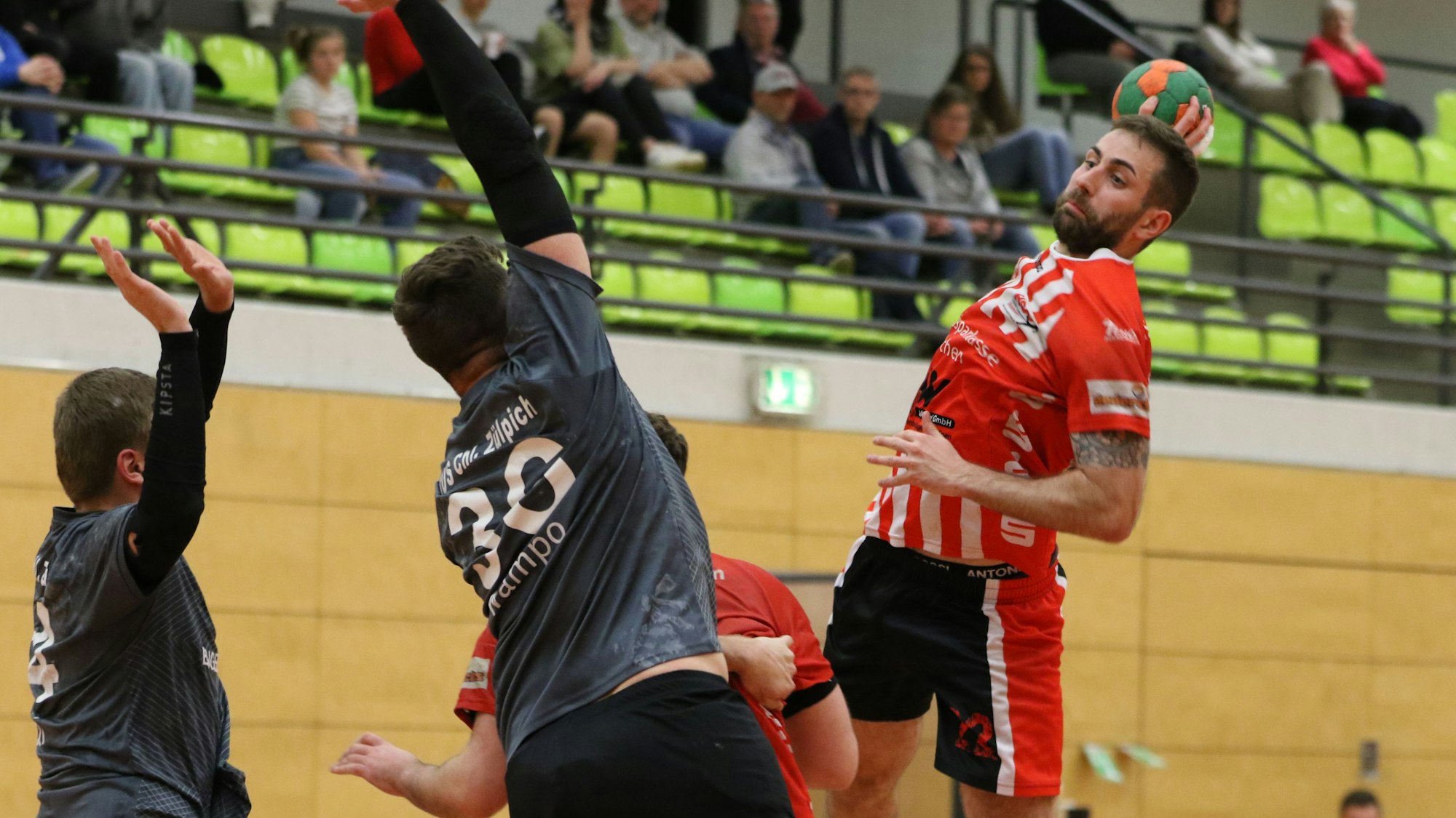 David Henzel bei einem Wurf. Zwei Gegenspieler steigen zum Block hoch.