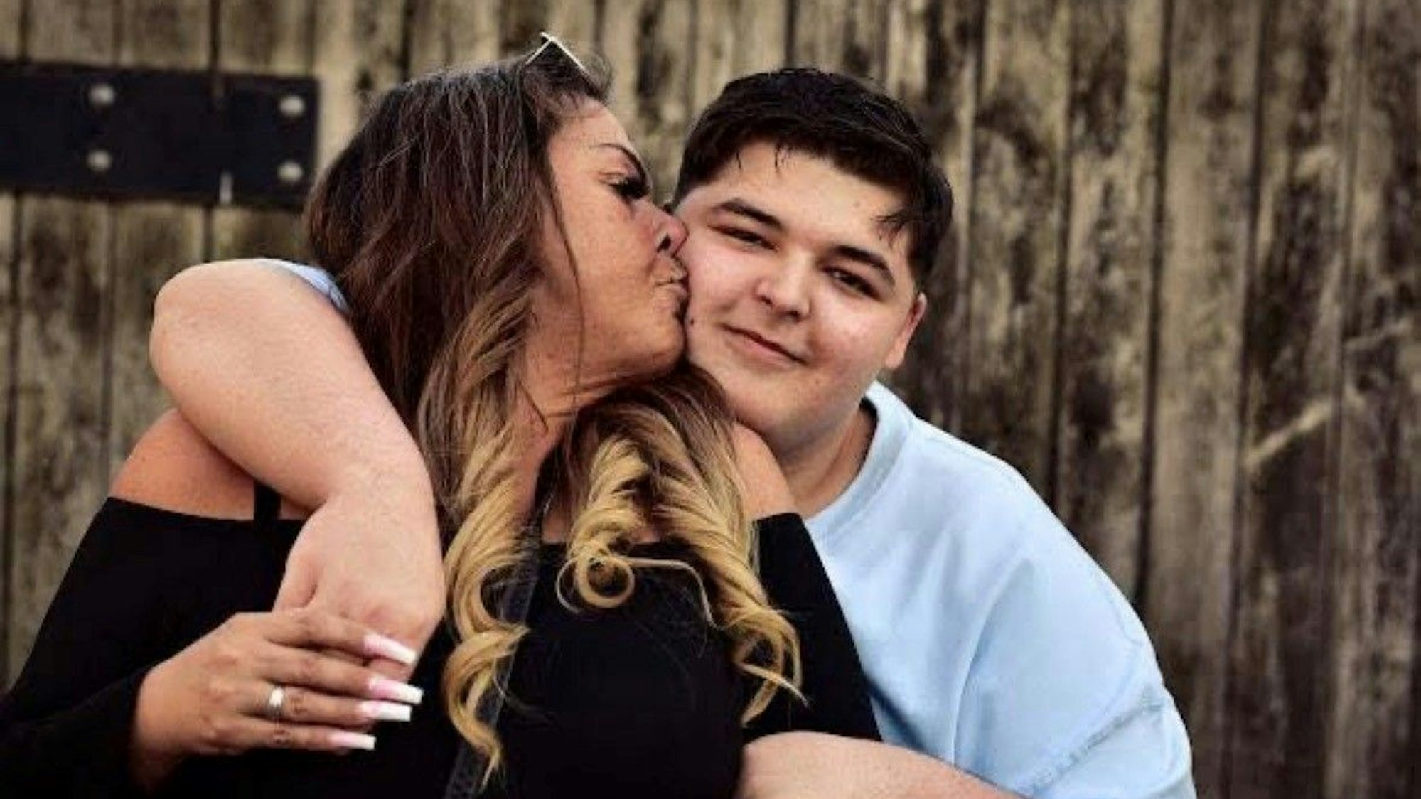 Auf dem Bild ist eine Mutter mit ihrem Sohn in inniger Umarmung zu sehen.