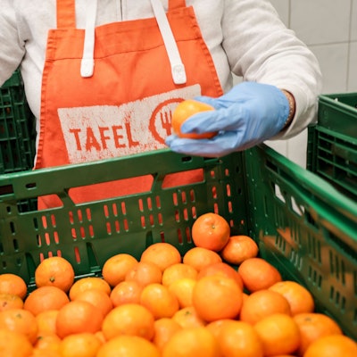 Eine Helferin mit einer Schürze mit Logo der Tafel sortiert bei der Tafel Bremerhaven Obst vor der Ausgabe an die Kunden.
