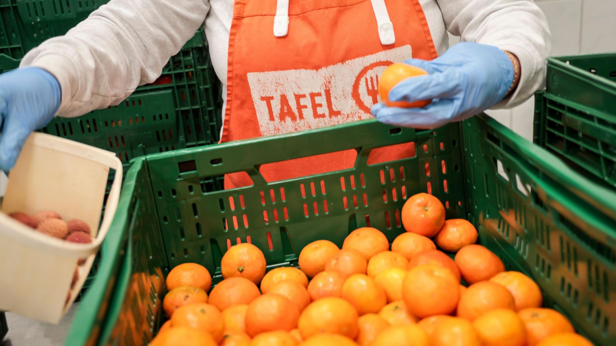 Eine Helferin mit einer Schürze mit Logo der Tafel sortiert bei der Tafel Bremerhaven Obst vor der Ausgabe an die Kunden.