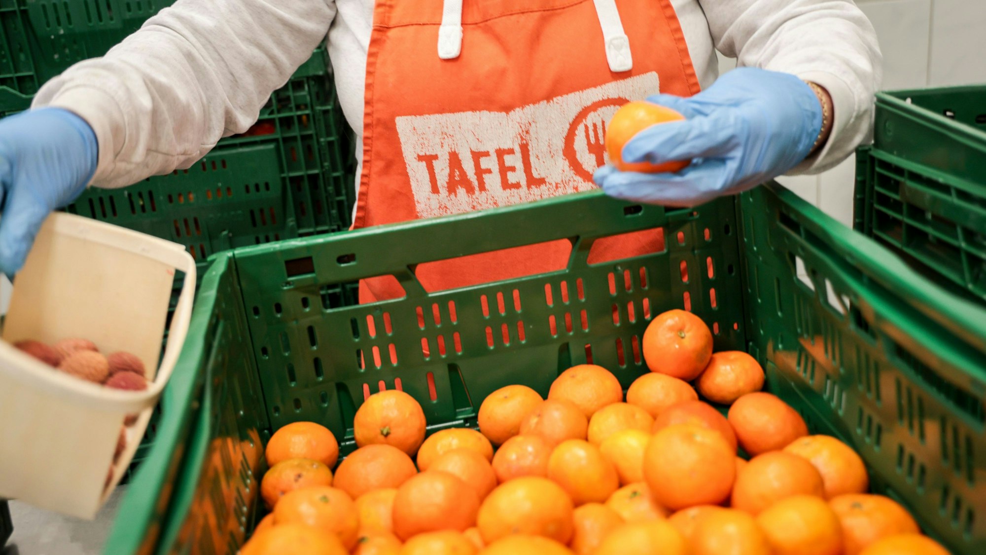 Eine Helferin mit einer Schürze mit Logo der Tafel sortiert bei der Tafel Bremerhaven Obst vor der Ausgabe an die Kunden.