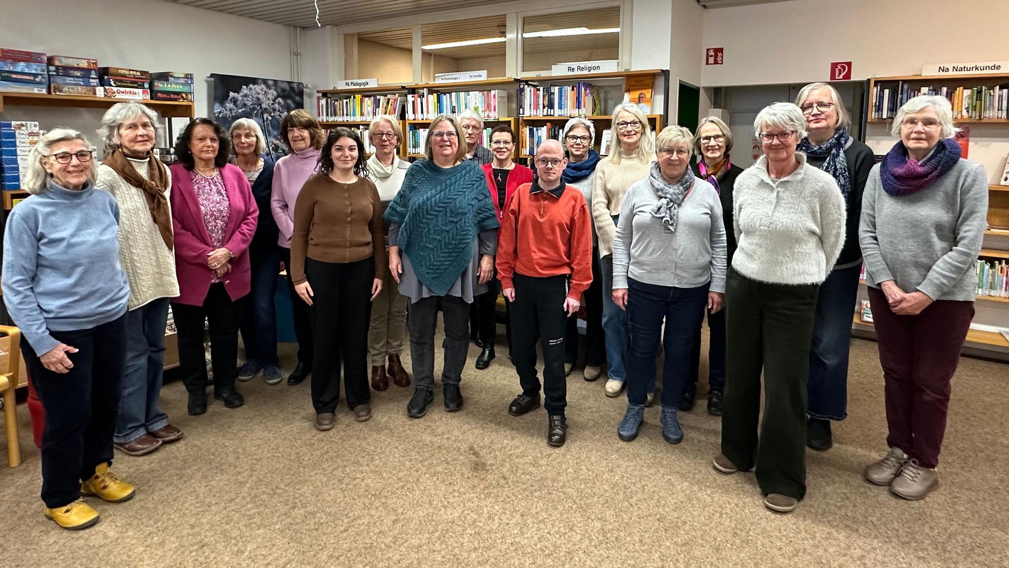 Das Overather Stadtbüchereiteam steht vor Regalen mit Büchern in der Stadtbibliothek.
