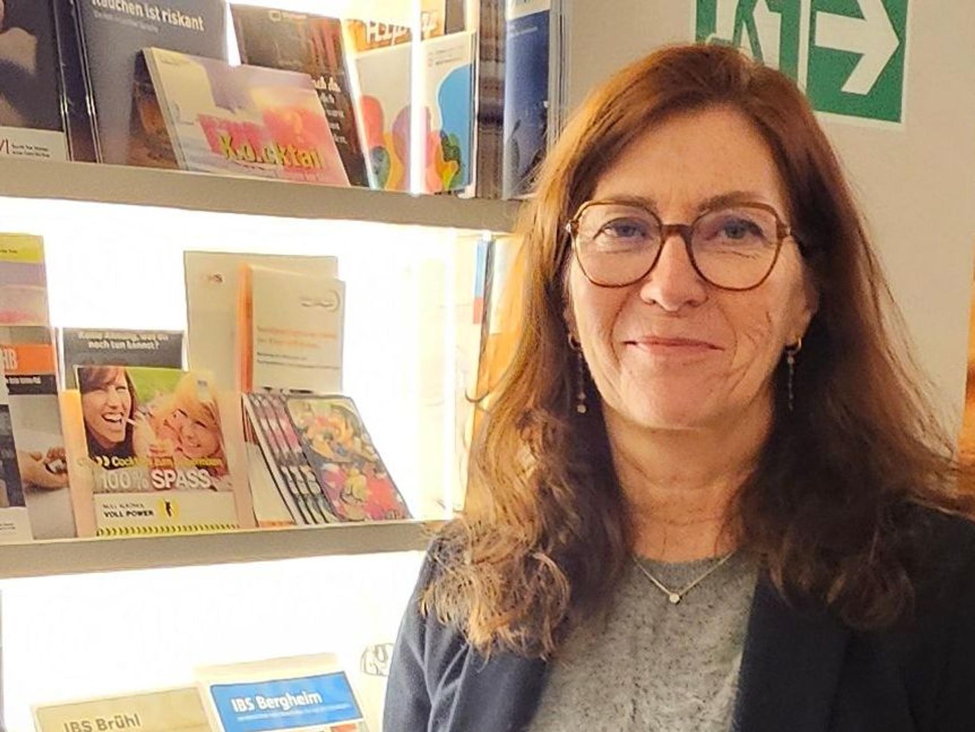 Das Foto zeigt die Referentin vor einem Regal mit Informaterial.