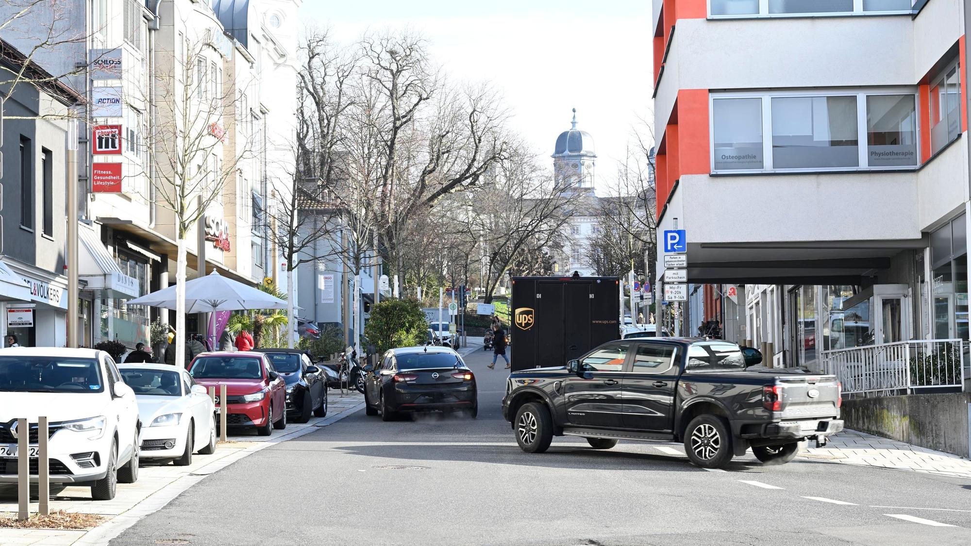 Zwei Autos fahren um einen Transporter im großen Bogen herum.