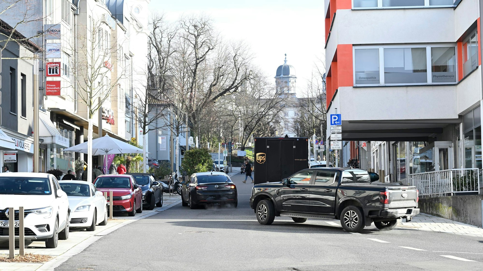 Zwei Autos fahren um einen Transporter im großen Bogen herum.