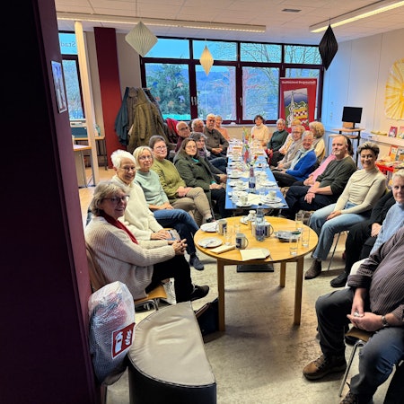 Zu sehen ist eine Versammlung von rund 20 Erwachsenen an einem Tisch