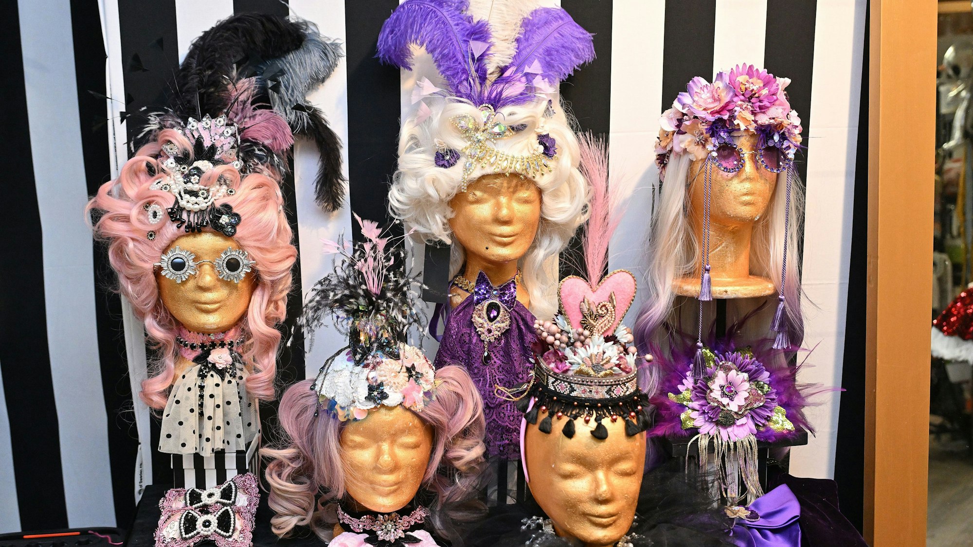 Goldene Perückenköpfe mit barocken Perücken und glitzernden Perlen.