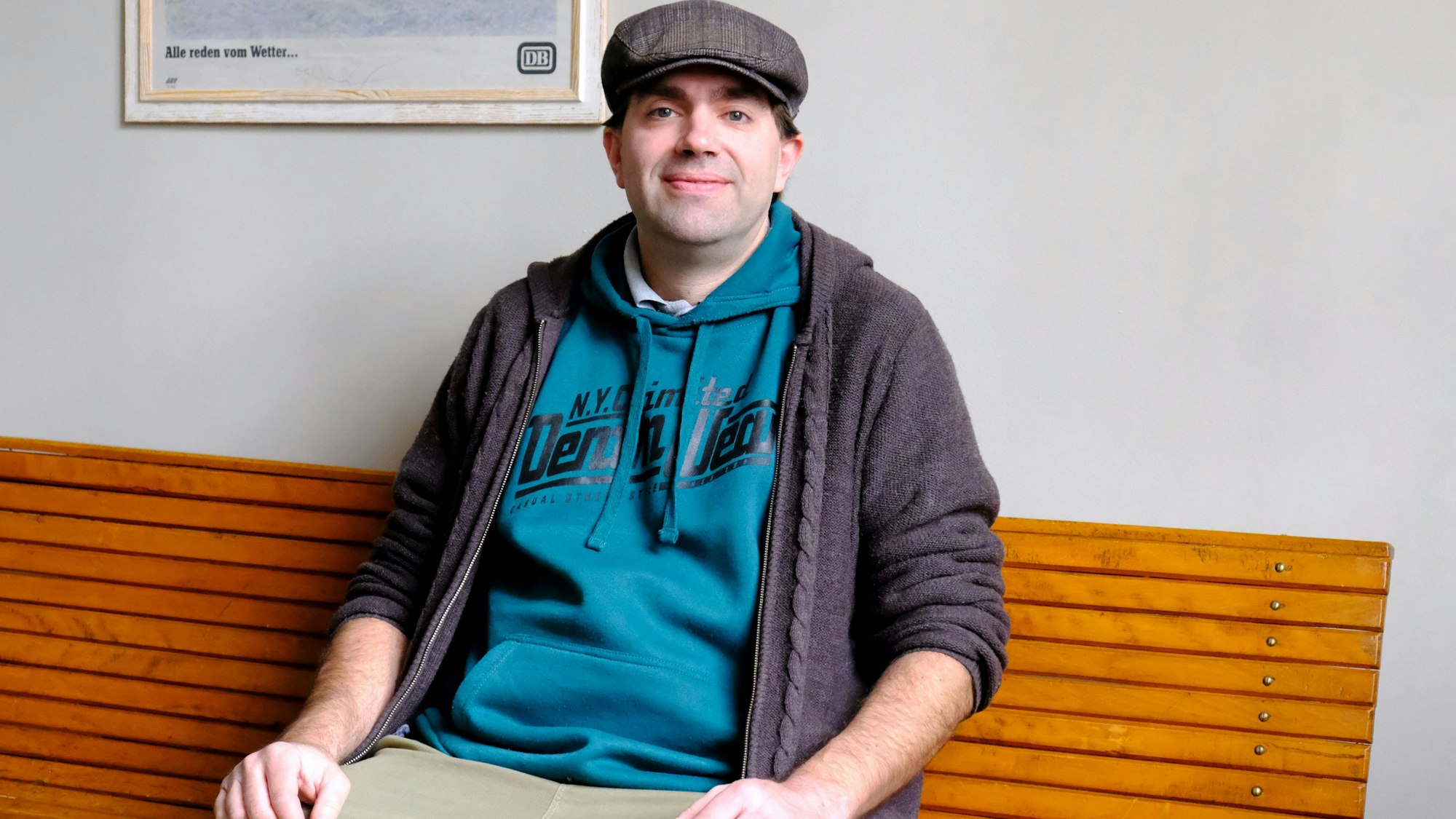 Andreas Kurth sitzt auf einer hölzernen Bank im Bahnhofs-Wartesaal in Ahütte.