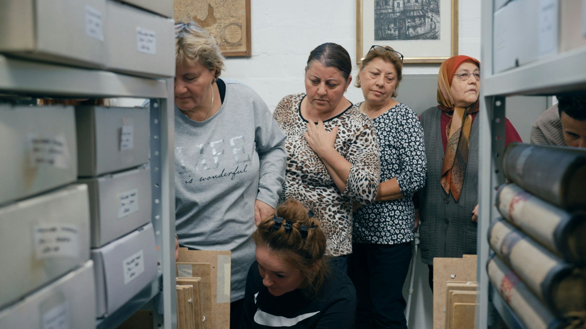 Frauen betrachten Kartons in einem Regal.
