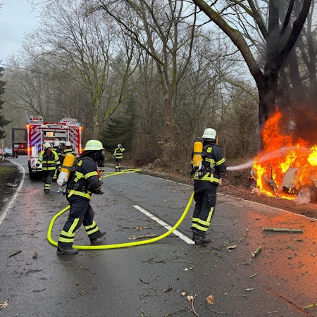 Das Bild zeigt Einsatzkräfte der Feuerwehr Lindlar beim Löschen des brennendes Pkw-Wracks.