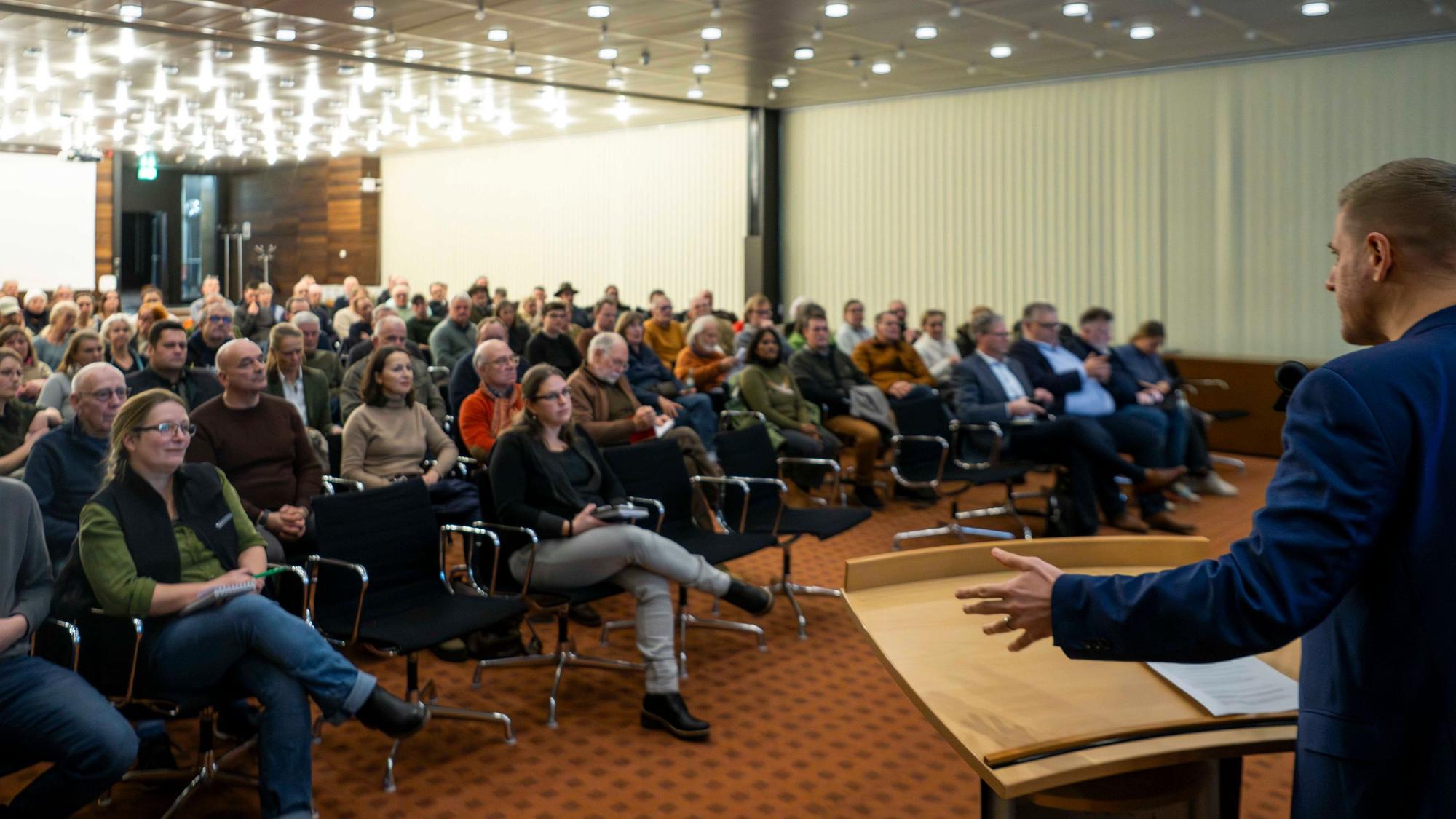 Landrat Markus Ramers spricht vor einer Gruppe Menschen, die im Sitzungssaal des Euskirchener Kreishauses Platz genommen haben.