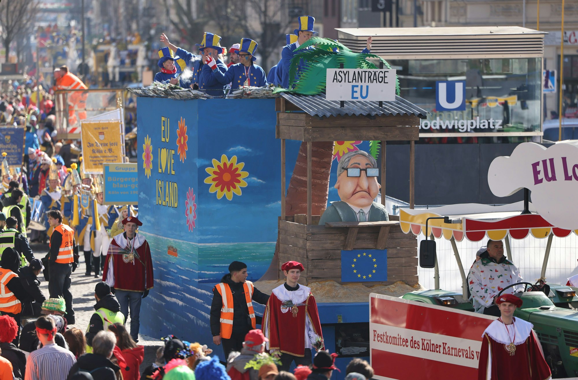 Ein Motivwagen zum Thema Einwanderung ("EU Love Island - Einreisen nach Europa") fährt durch die Straße. Mit den Rosenmontagszügen erreicht der rheinische Straßenkarneval seinen Höhepunkt. Das Motto der Kölner Karnevalssession 2025 lautet «FasteLOVEnd - Wenn Dräum widder blöhe». +++ dpa-Bildfunk +++