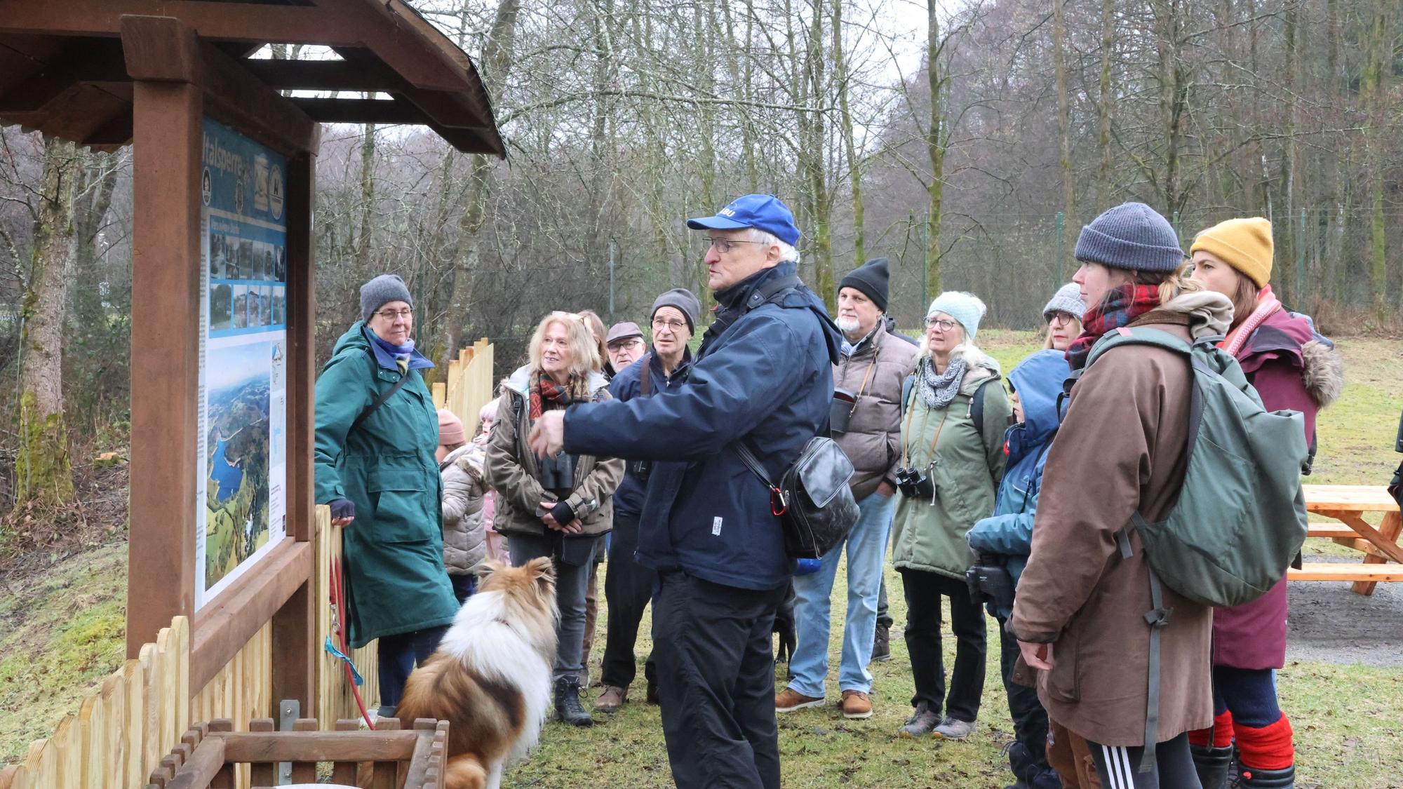 Eine Gruppe steht vor einer Infotafel in der Natur.