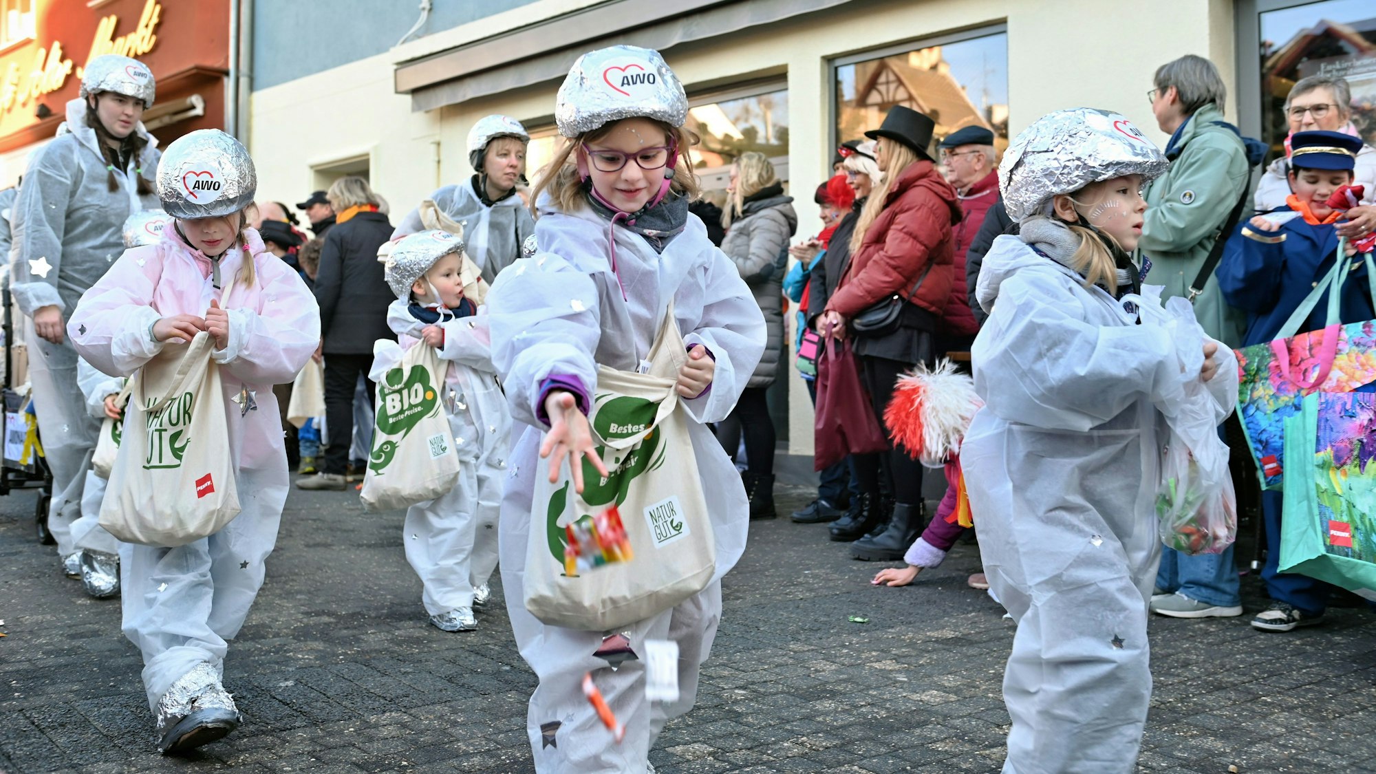 Kinder in Glitzerkostümen gehen im Karnevalszug durch Euskirchen.