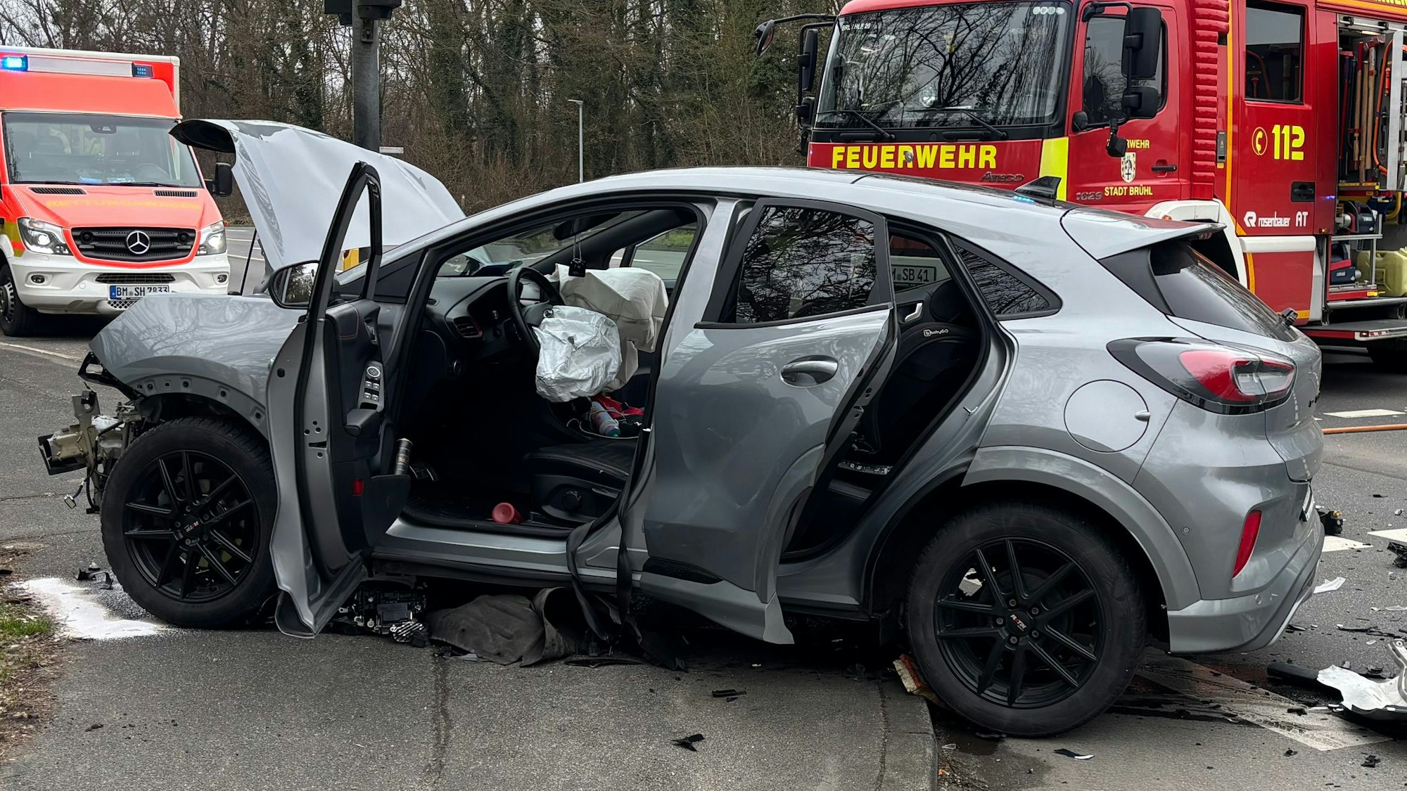 Im Vordergrund ein Fahrzeug mit Unfallspuren. Gas- und Fahrzeugsplitter lagen weit über die Kreuzung verteilt. Im Hintergrund Feuerwehr- und Notarztfahrzeuge.