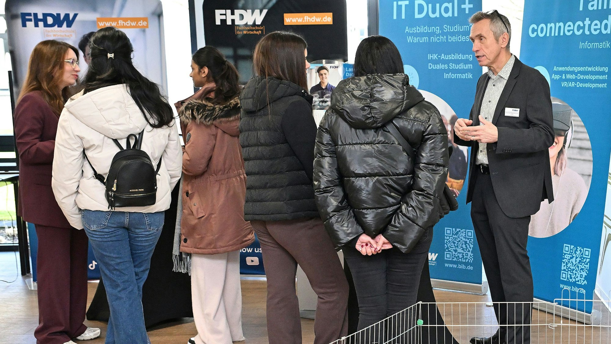 Besucher sprechen in den Räumlichkeiten der Fachhochschule mit Dozierenden.