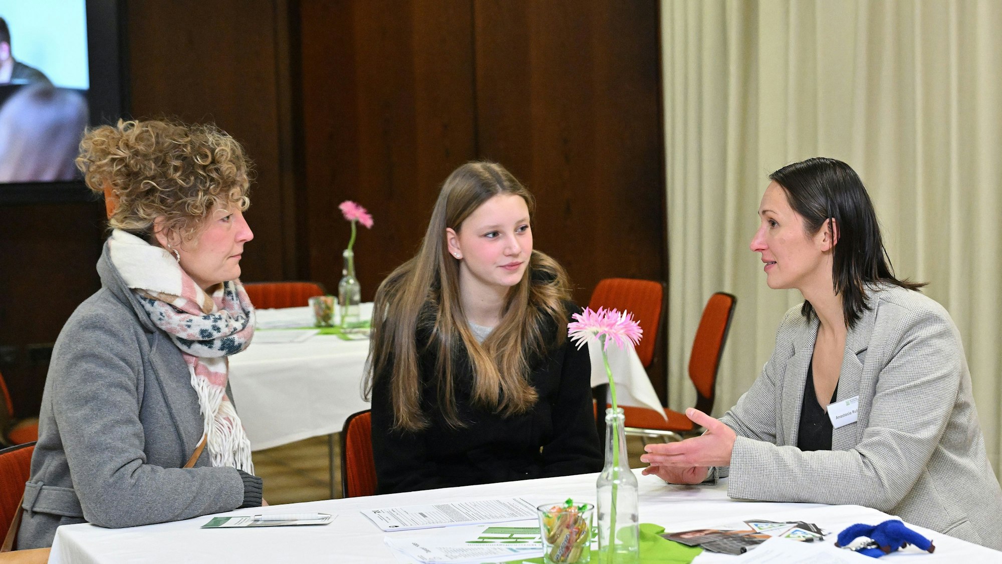 Die Mitarbeiterin eines Unternehmens stellt sich bei einer Schülerin vor.